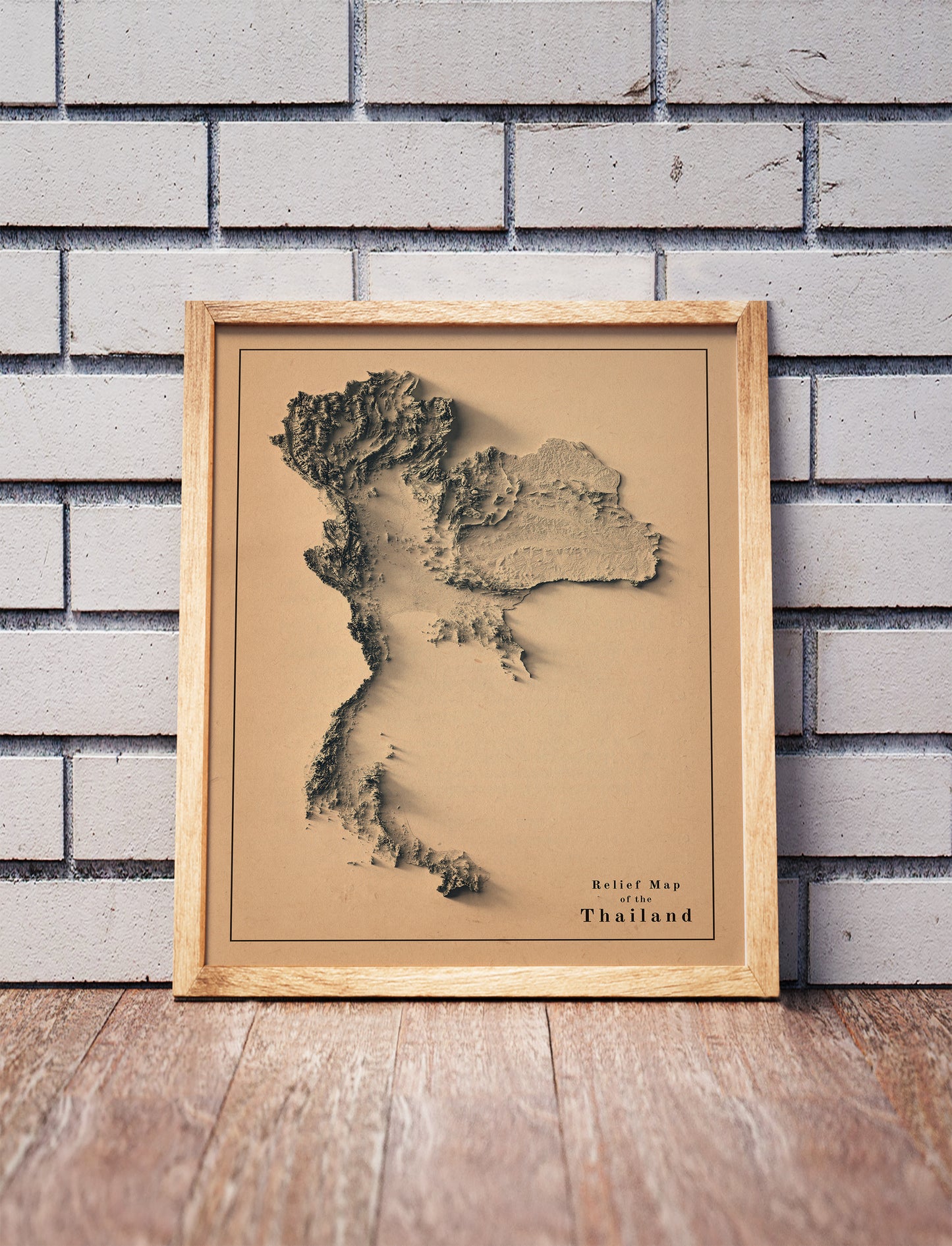 Vintage Thailand shaded relief map in a wooden frame. Realistic terrain art print for home decor, displayed against a brick wall