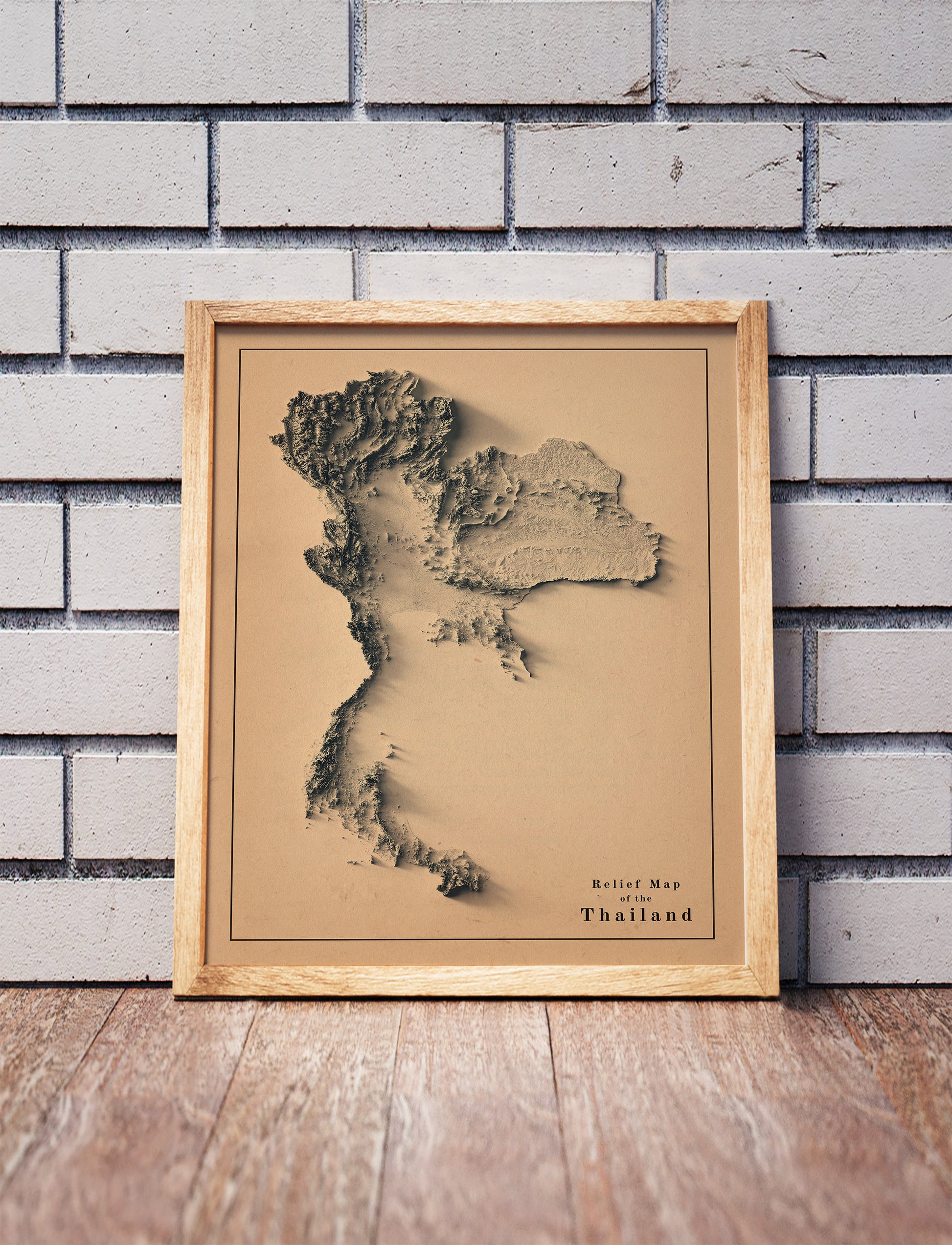 Vintage Thailand shaded relief map in a wooden frame. Realistic terrain art print for home decor, displayed against a brick wall
