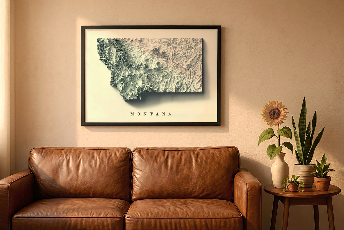Montana relief map in a black frame above a brown leather sofa. Boho living room with warm sunlight, sunflower, and indoor plants on a wooden side table