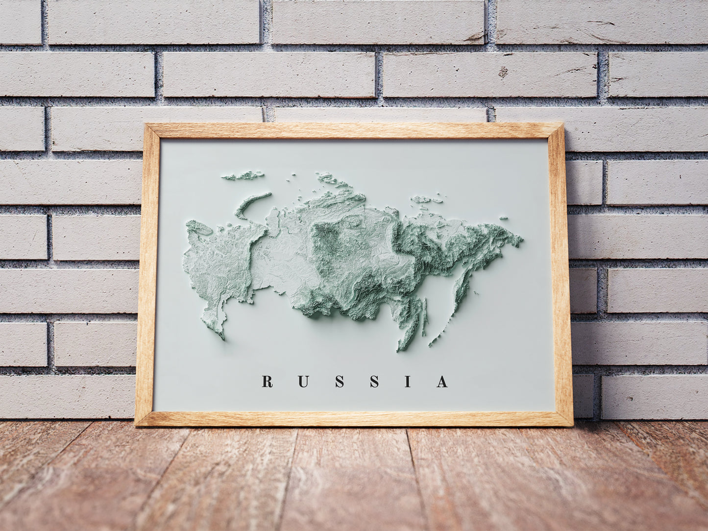 Russia shaded relief map in a wooden frame. Realistic terrain art print for home decor, displayed against a brick wall