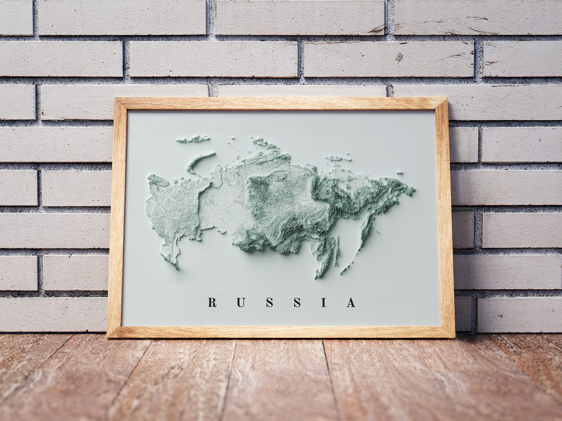 Russia shaded relief map in a wooden frame. Realistic terrain art print for home decor, displayed against a brick wall