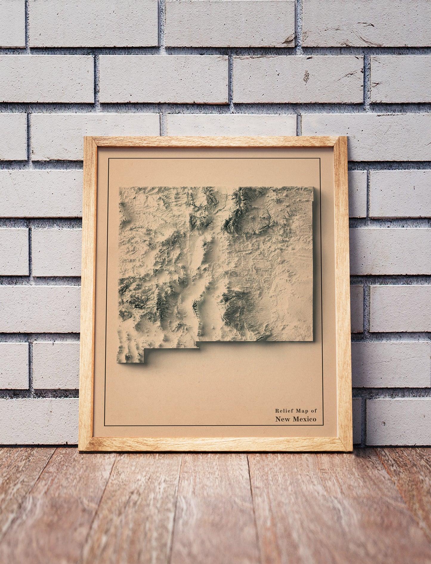 Vintage New Mexico shaded relief map in a wooden frame. Realistic terrain art print for home decor, displayed against a brick wall