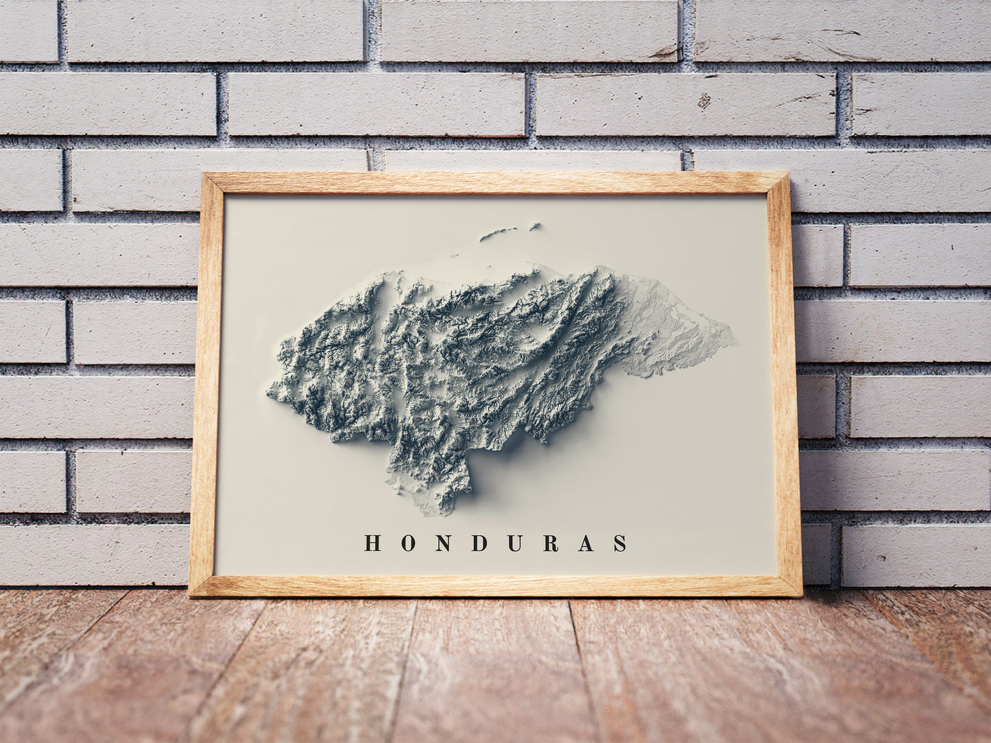 Honduras shaded relief map in a wooden frame. Realistic terrain art print for home decor, displayed against a brick wall