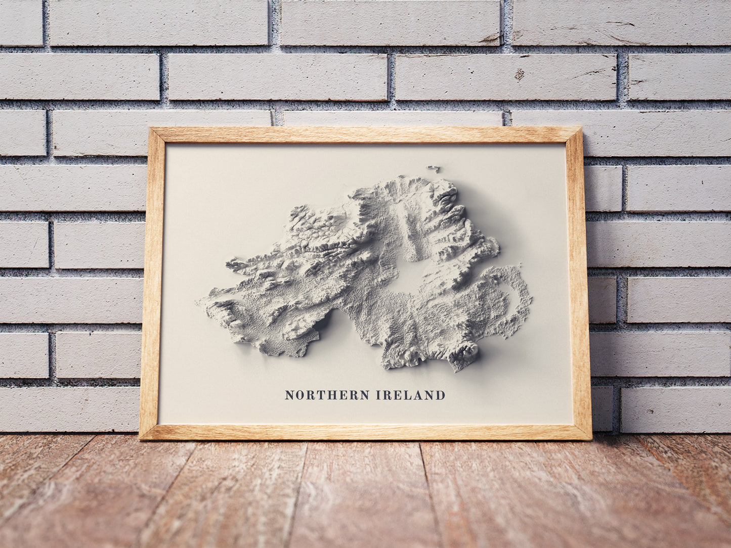 northern ireland shaded relief map in a wooden frame. Realistic terrain art print for home decor, displayed against a brick wall