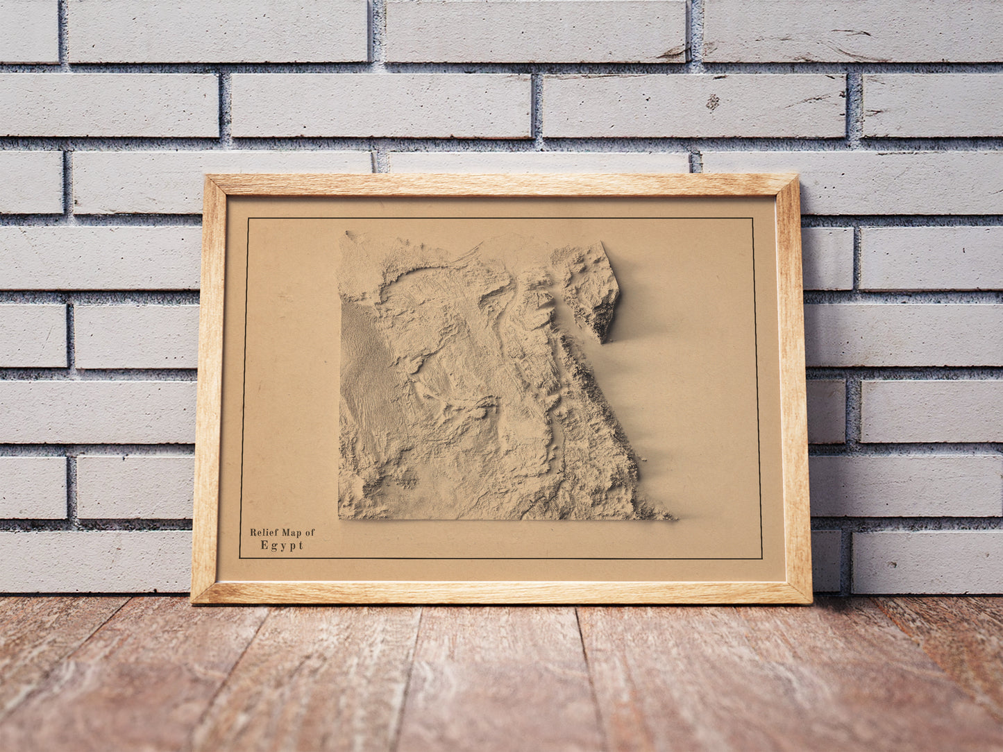 Vintage Egypt shaded relief map in a wooden frame. Realistic terrain art print for home decor, displayed against a brick wall