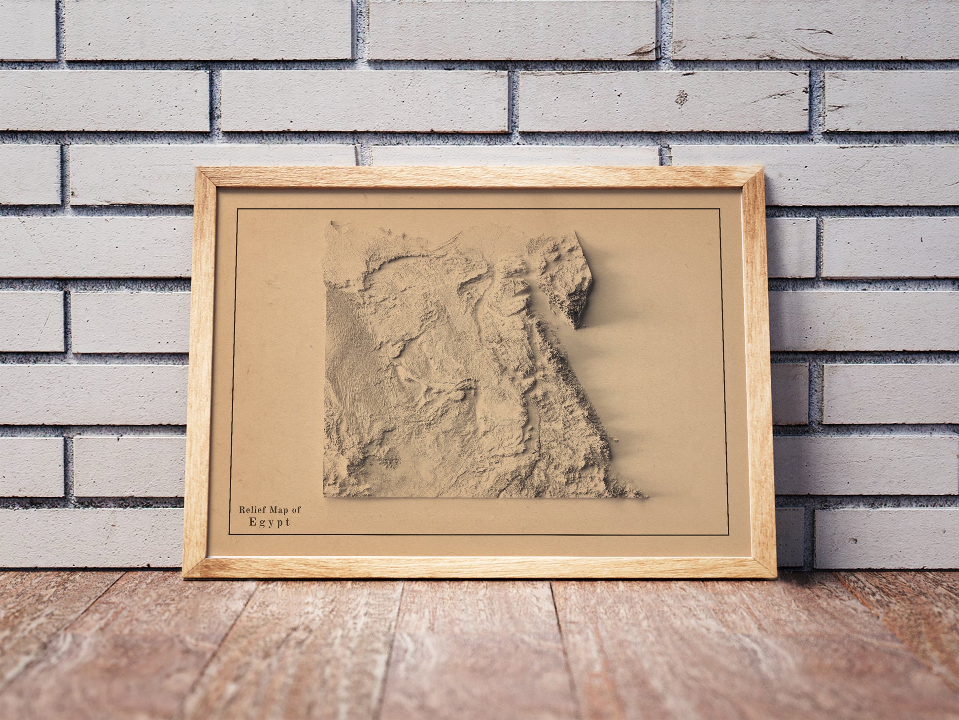 Vintage Egypt shaded relief map in a wooden frame. Realistic terrain art print for home decor, displayed against a brick wall