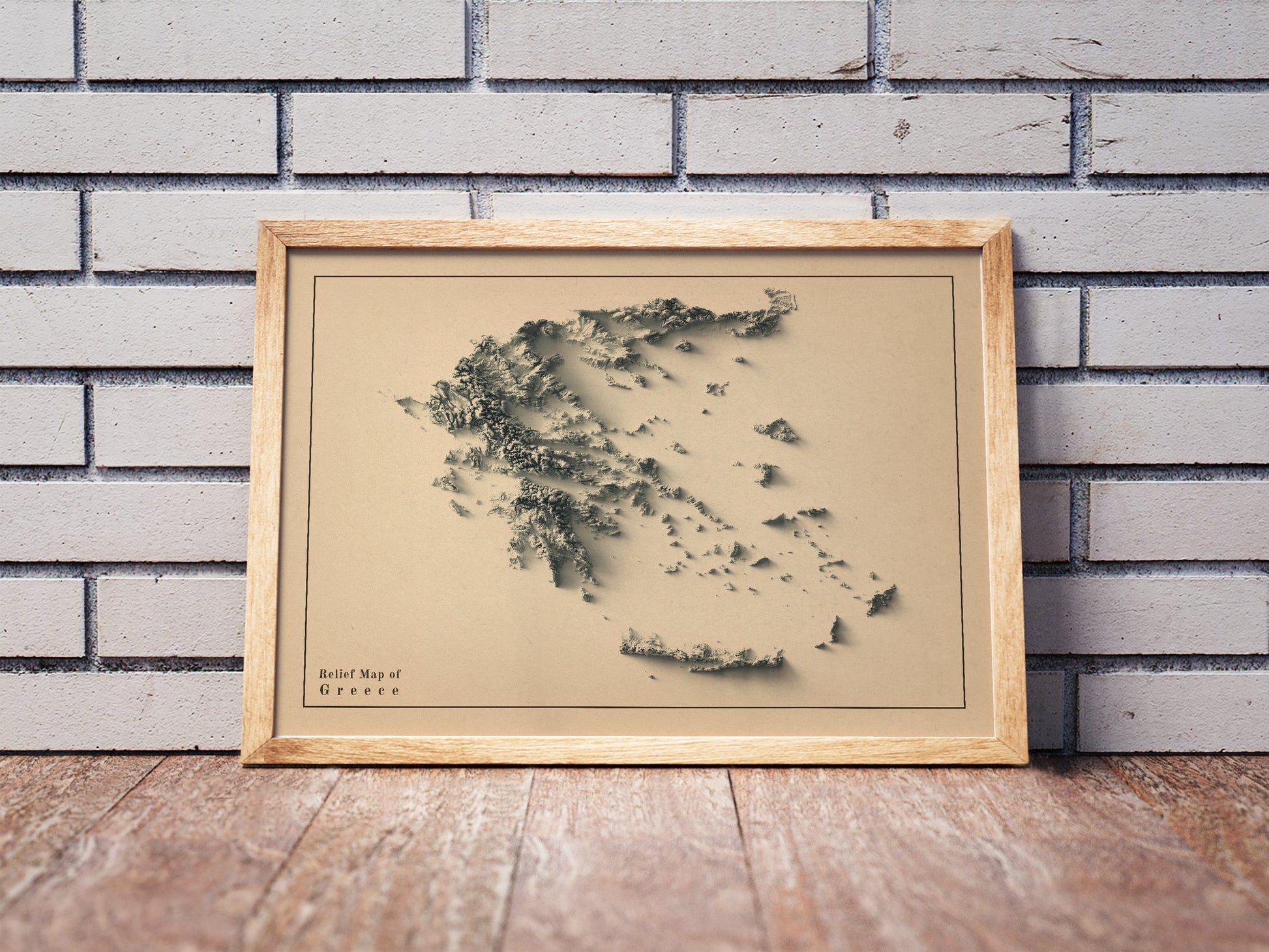 Vintage Greece shaded relief map in a wooden frame. Realistic terrain art print for home decor, displayed against a brick wall