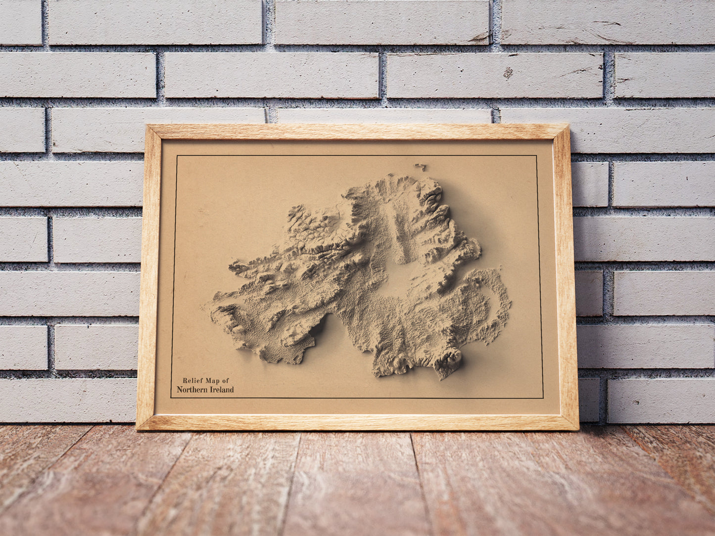 northern ireland shaded relief map in a wooden frame. Realistic terrain art print for home decor, displayed against a brick wall