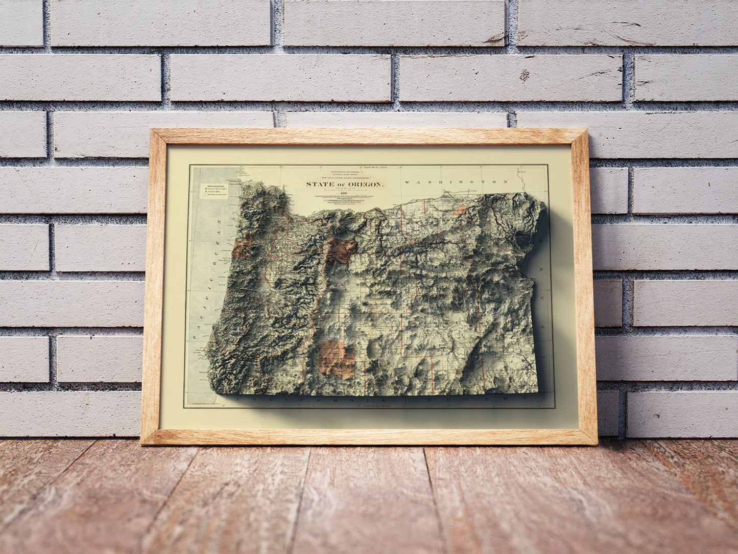 Vintage Oregon shaded relief map in a wooden frame. Realistic terrain art print for home decor, displayed against a brick wall