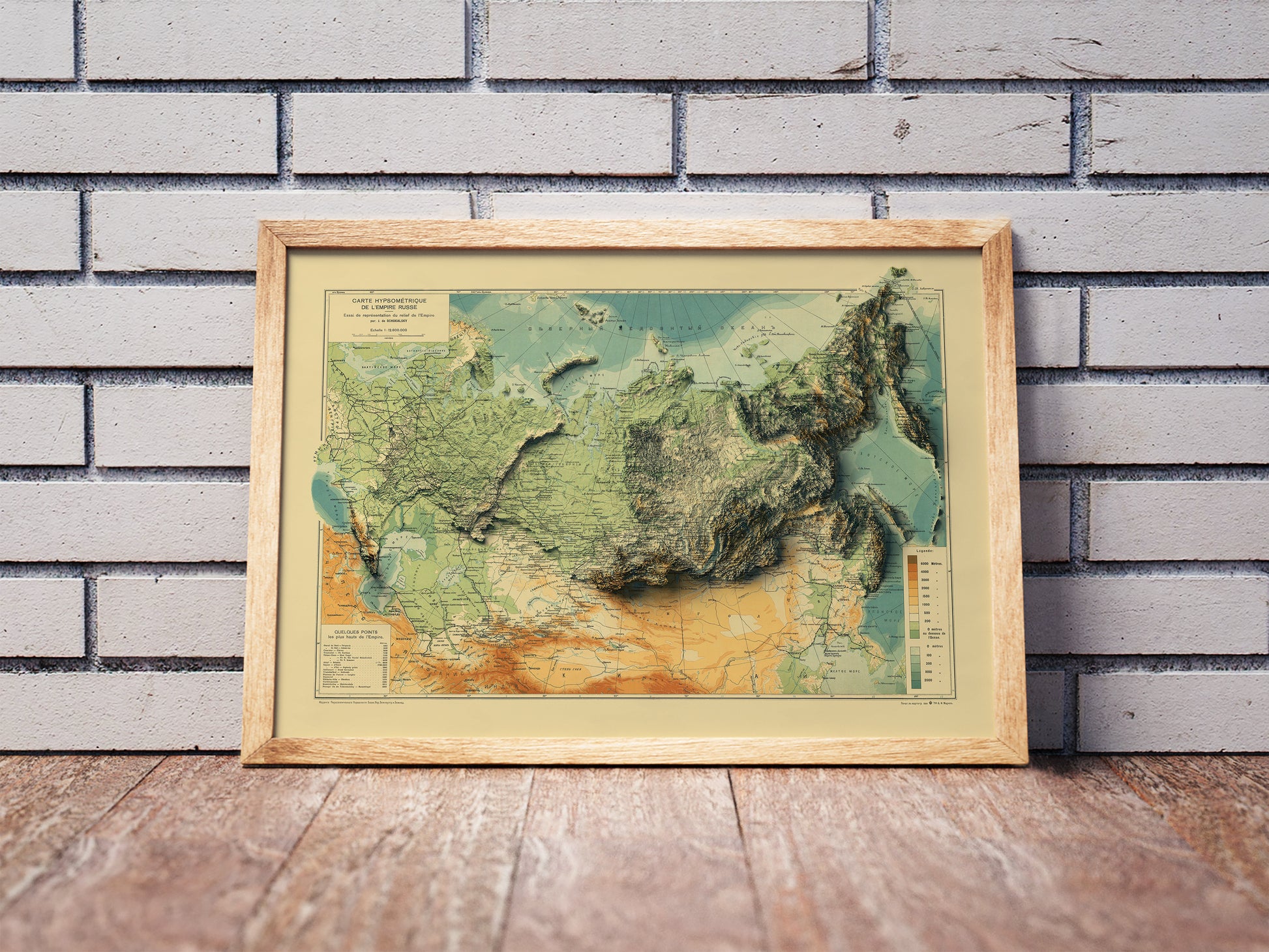 Vintage Russia shaded relief map in a wooden frame. Realistic terrain art print for home decor, displayed against a brick wall