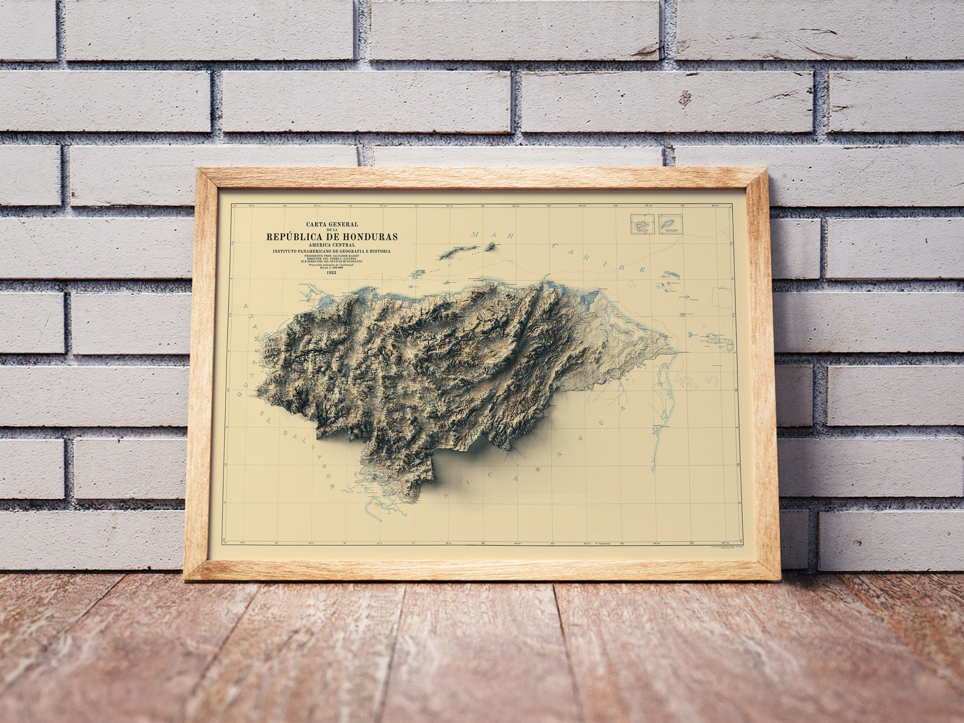 Vintage Honduras shaded relief map in a wooden frame. Realistic terrain art print for home decor, displayed against a brick wall