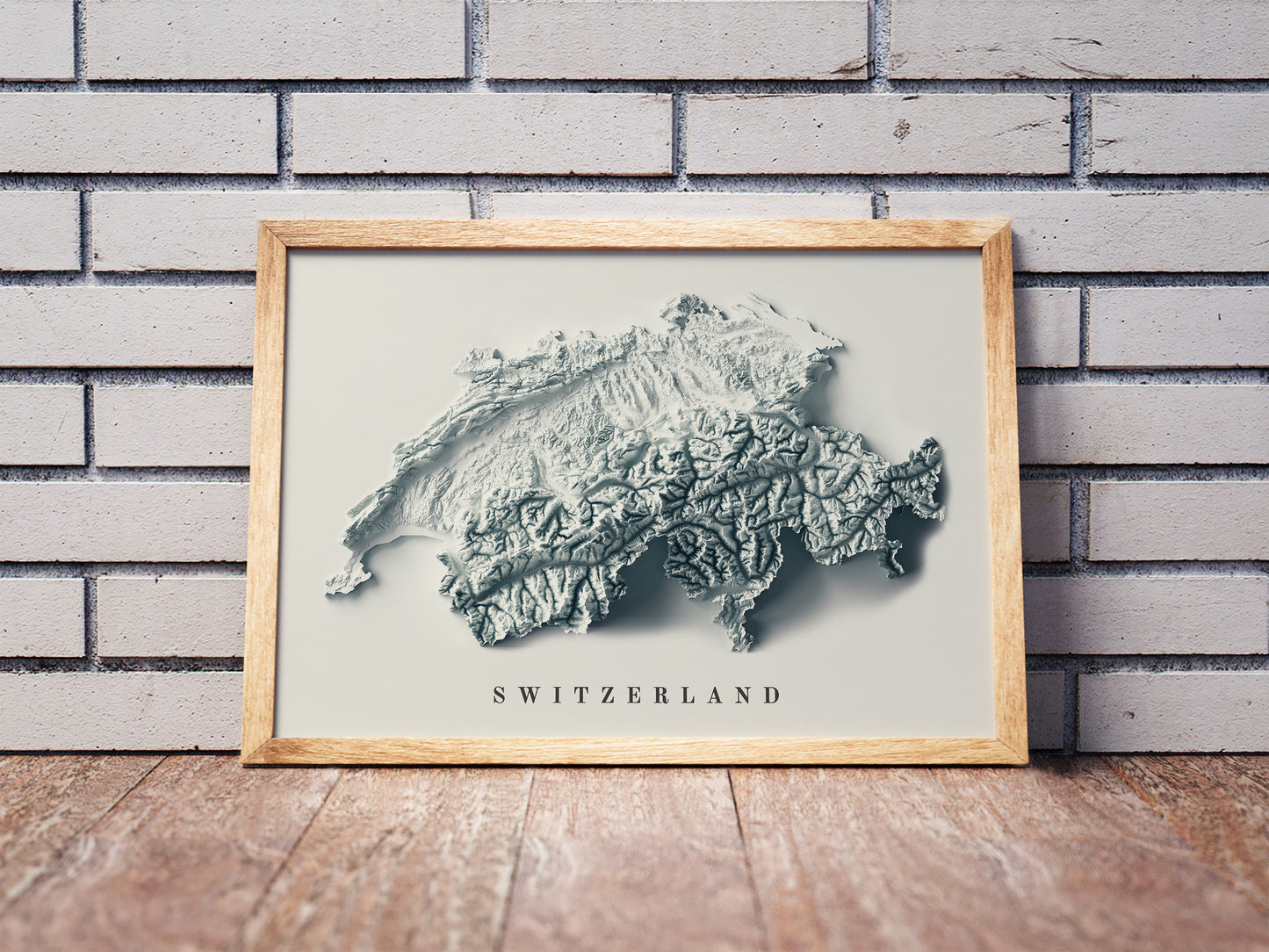 Switzerland shaded relief map in a wooden frame. Realistic terrain art print for home decor, displayed against a brick wall