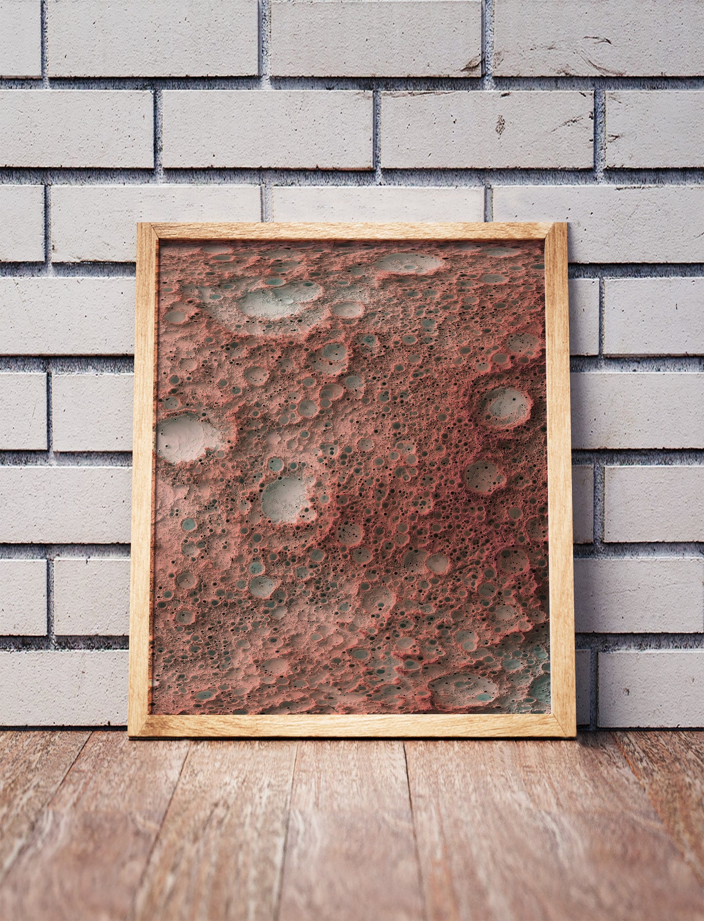 Moon shaded relief map in a wooden frame. Realistic terrain art print for home decor, displayed against a brick wall