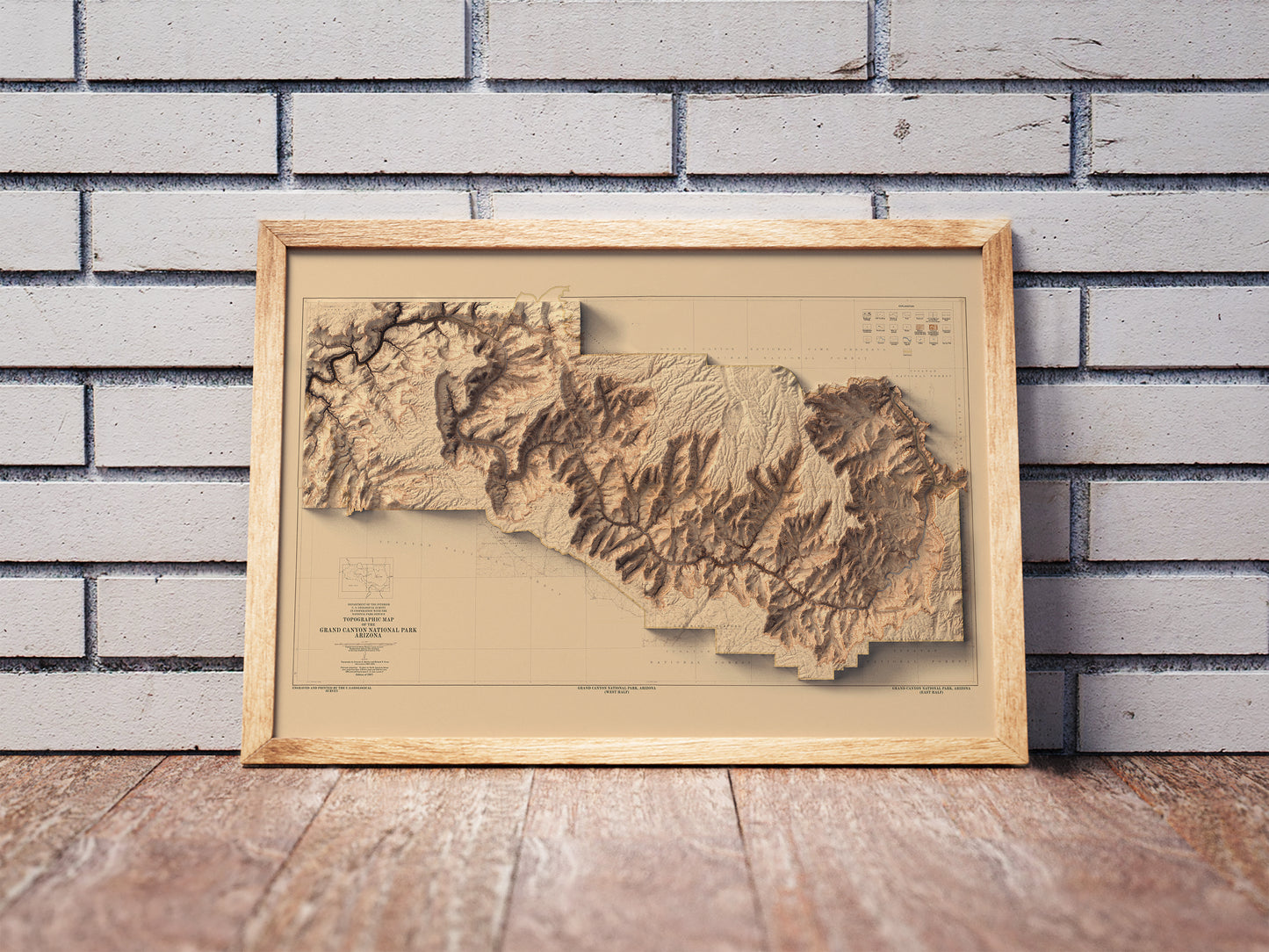 Vintage Grand Canyon shaded relief map in a wooden frame. Realistic terrain art print for home decor, displayed against a brick wall
