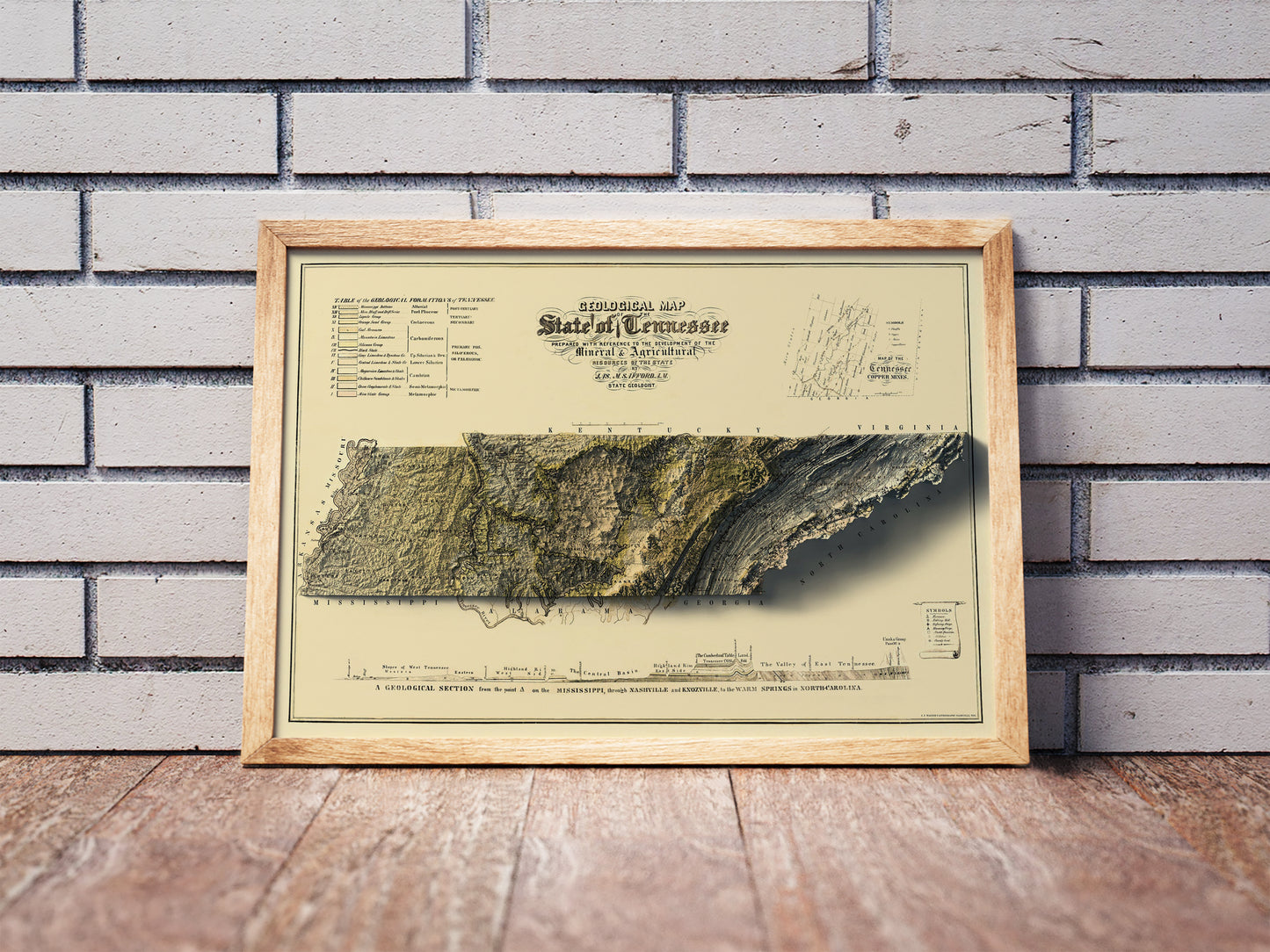 Vintage Tennessee shaded relief map in a wooden frame. Realistic terrain art print for home decor, displayed against a brick wall