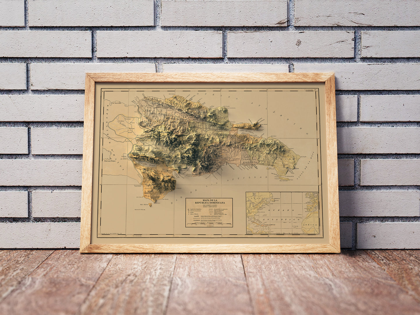 Vintage Dominican Republic shaded relief map in a wooden frame. Realistic terrain art print for home decor, displayed against a brick wall