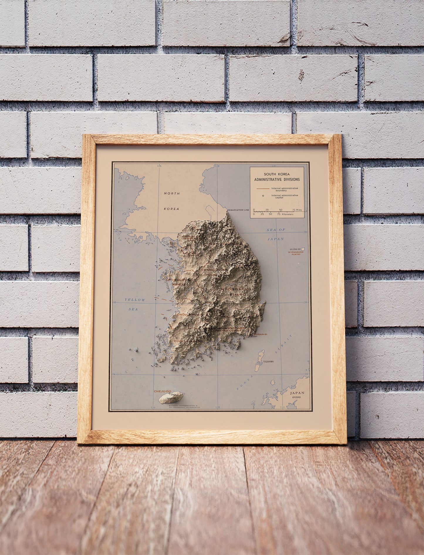 Vintage South Korea shaded relief map in a wooden frame. Realistic terrain art print for home decor, displayed against a brick wall