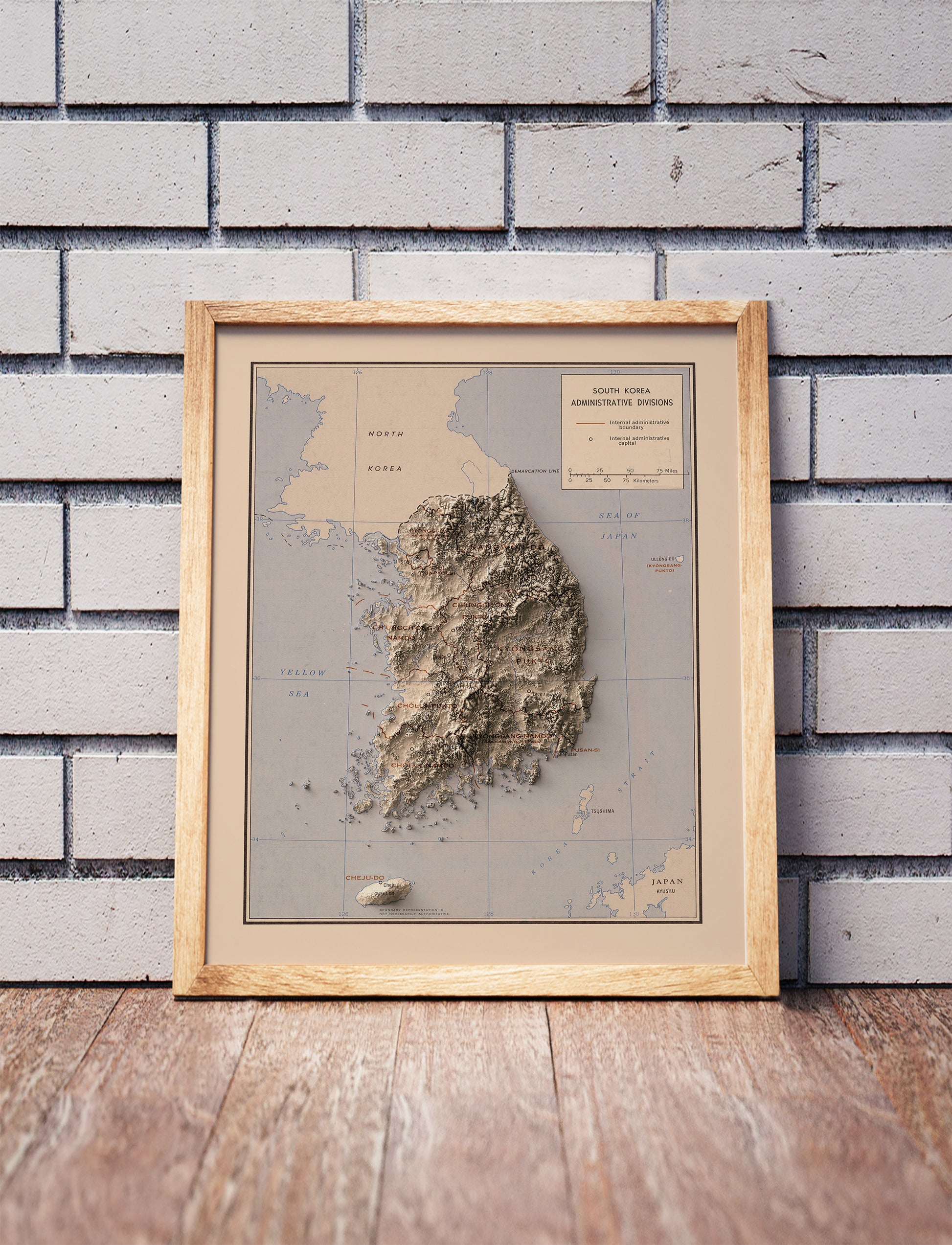 Vintage South Korea shaded relief map in a wooden frame. Realistic terrain art print for home decor, displayed against a brick wall