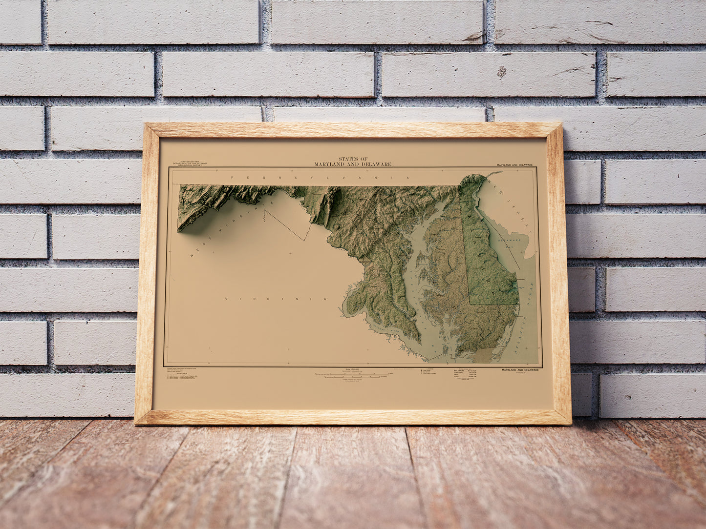 Vintage Maryland shaded relief map in a wooden frame. Realistic terrain art print for home decor, displayed against a brick wall