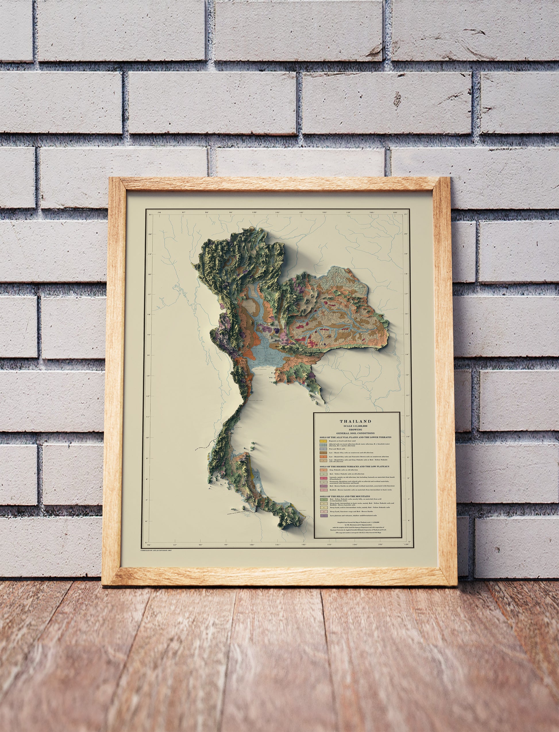Vintage Thailand shaded relief map in a wooden frame. Realistic terrain art print for home decor, displayed against a brick wall