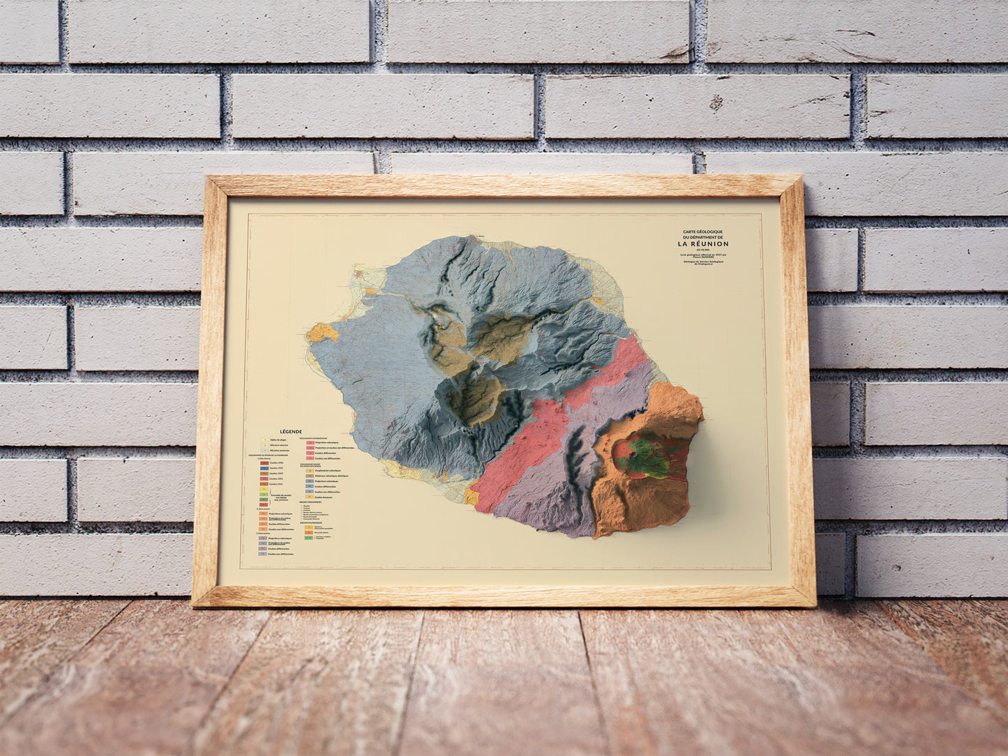 Vintage Reunion, France, shaded relief map in a wooden frame. Realistic terrain art print for home decor, displayed against a brick wall