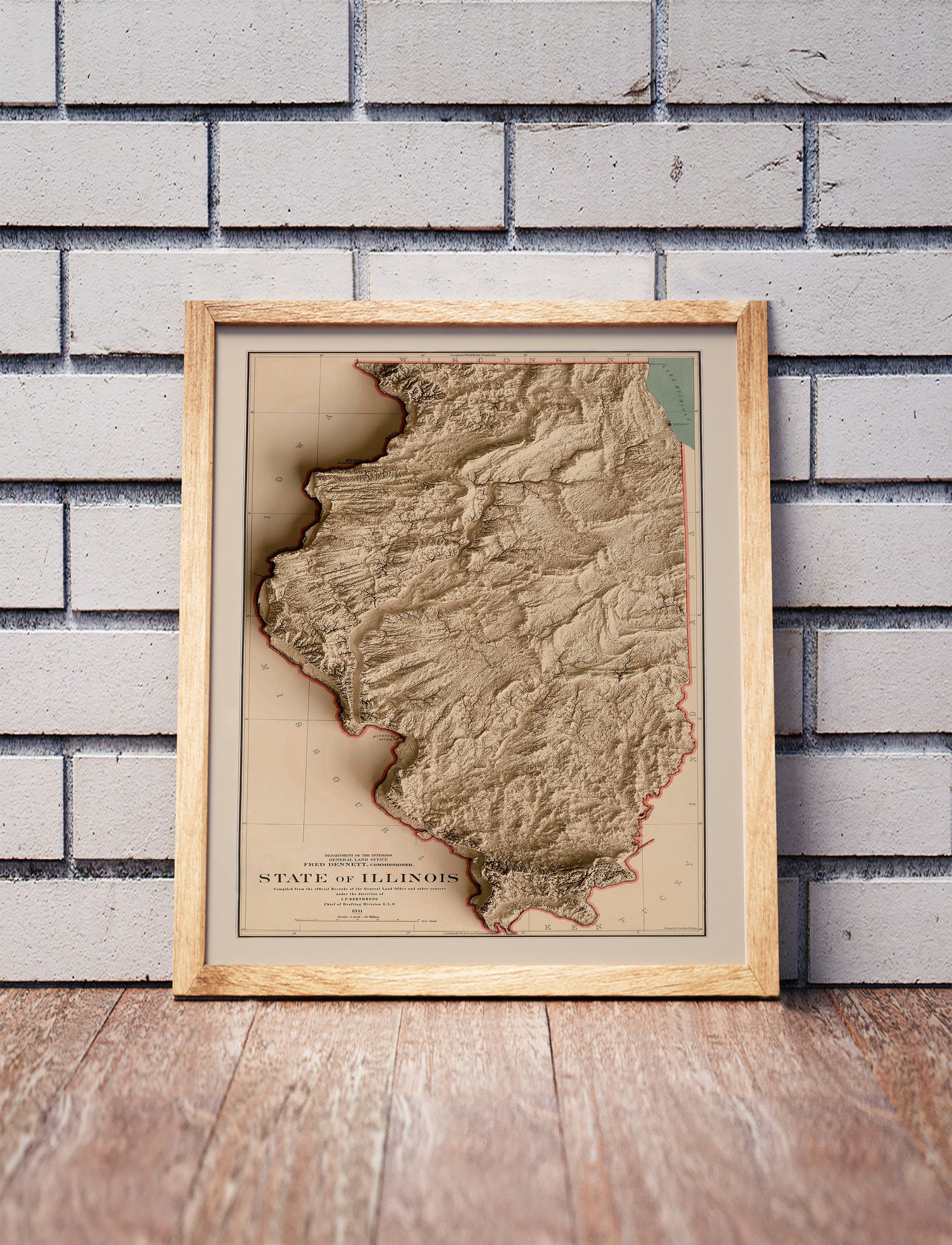 Vintage Illinois shaded relief map in a wooden frame. Realistic terrain art print for home decor, displayed against a brick wall