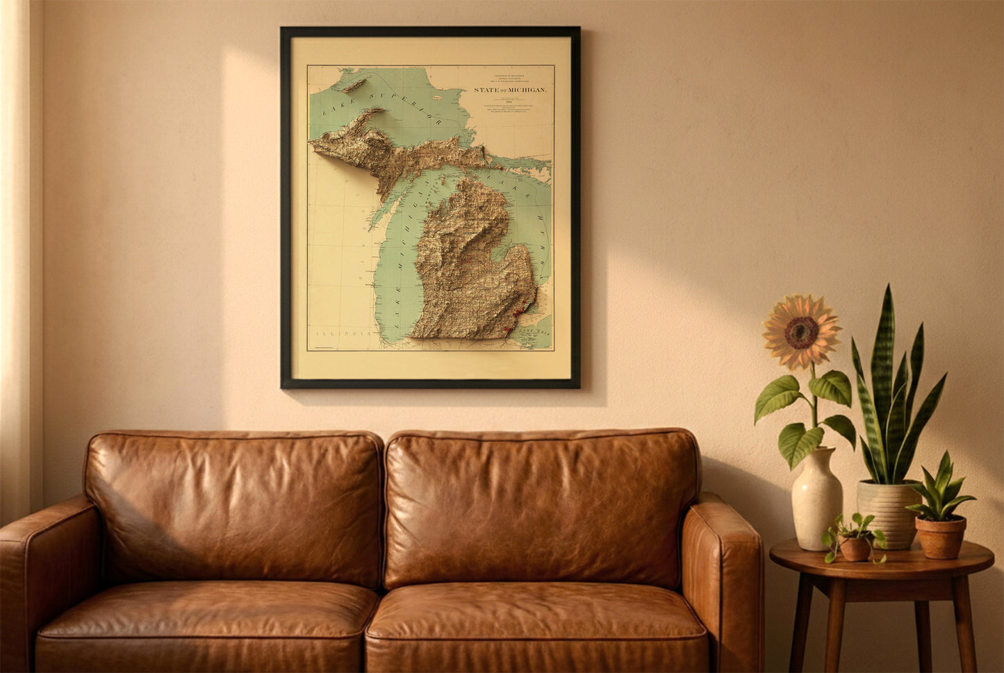 Michigan vintage relief map in a black frame above a brown leather sofa. Boho living room with warm sunlight, sunflower, and indoor plants on a wooden side table