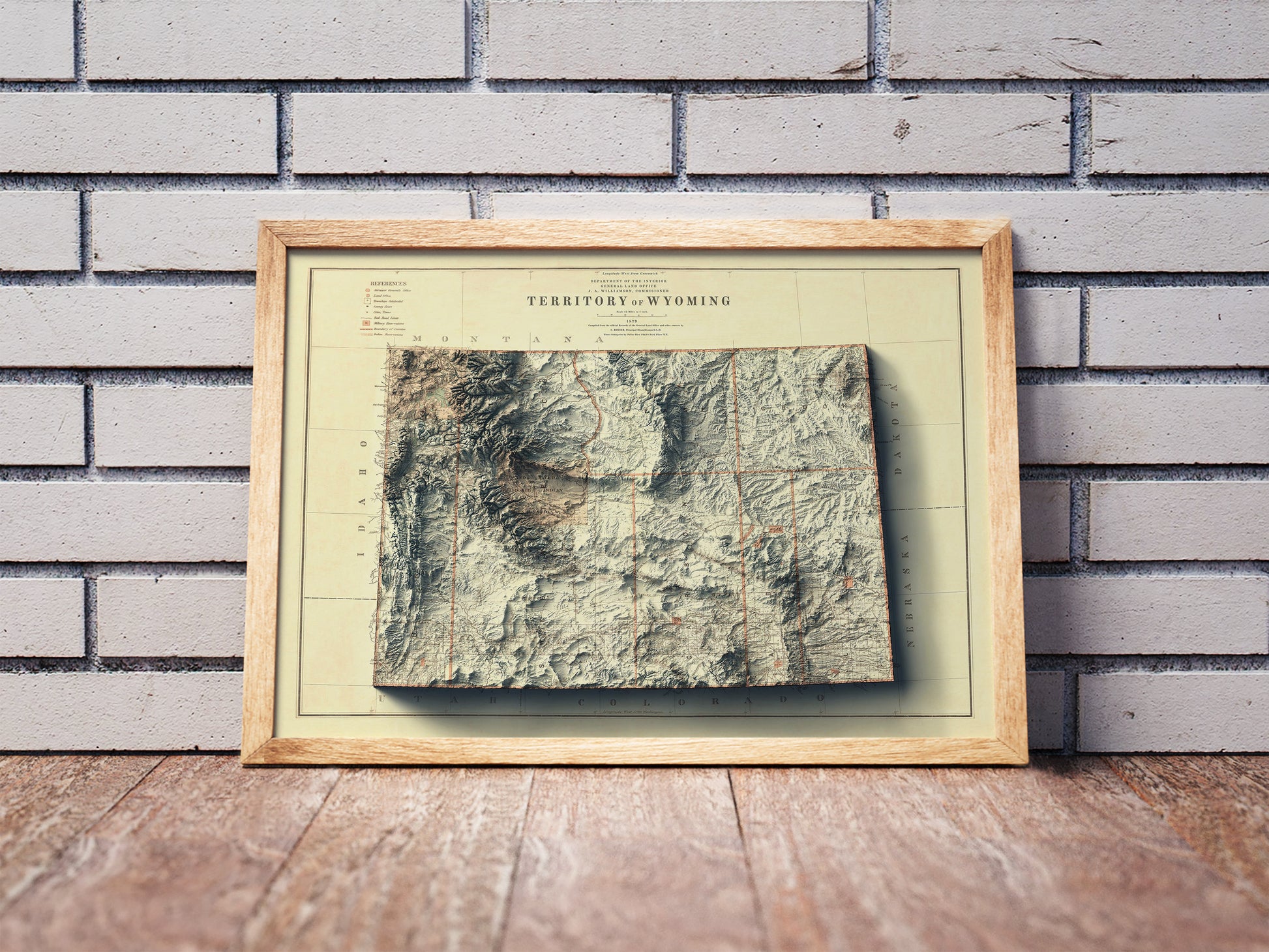 Vintage Wyoming shaded relief map in a wooden frame. Realistic terrain art print for home decor, displayed against a brick wall