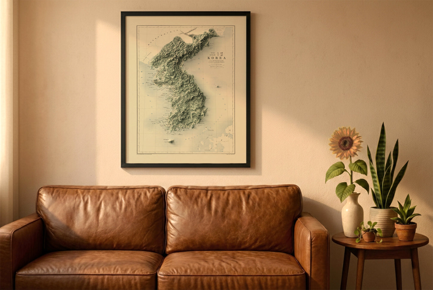 Koreas vintage relief map in a black frame above a brown leather sofa. Boho living room with warm sunlight, sunflower, and indoor plants on a wooden side table