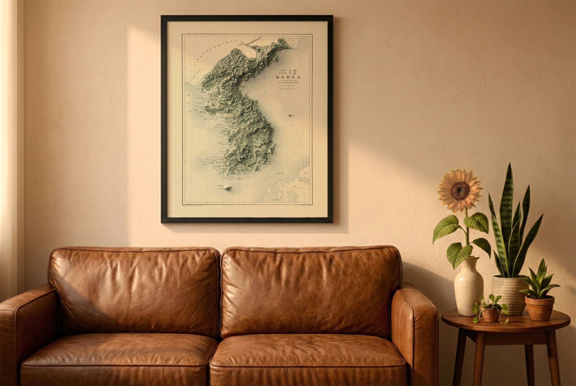 Koreas vintage relief map in a black frame above a brown leather sofa. Boho living room with warm sunlight, sunflower, and indoor plants on a wooden side table