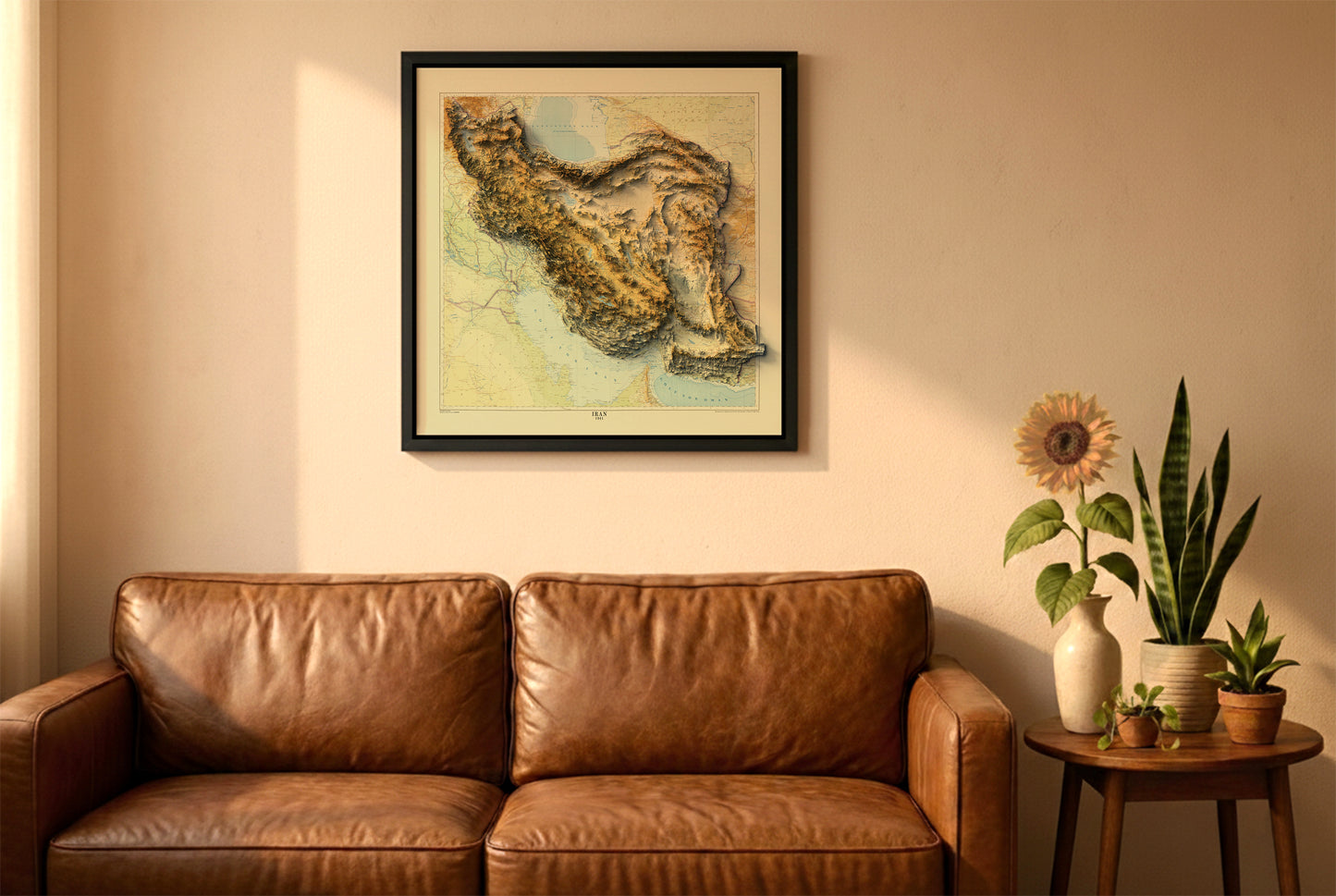 Iran vintage relief map in a black frame above a brown leather sofa. Boho living room with warm sunlight, sunflower, and indoor plants on a wooden side table