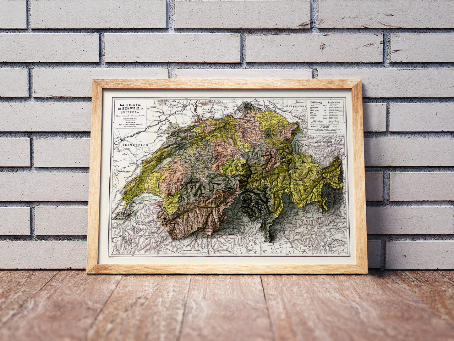 Vintage Switzerland shaded relief map in a wooden frame. Realistic terrain art print for home decor, displayed against a brick wall