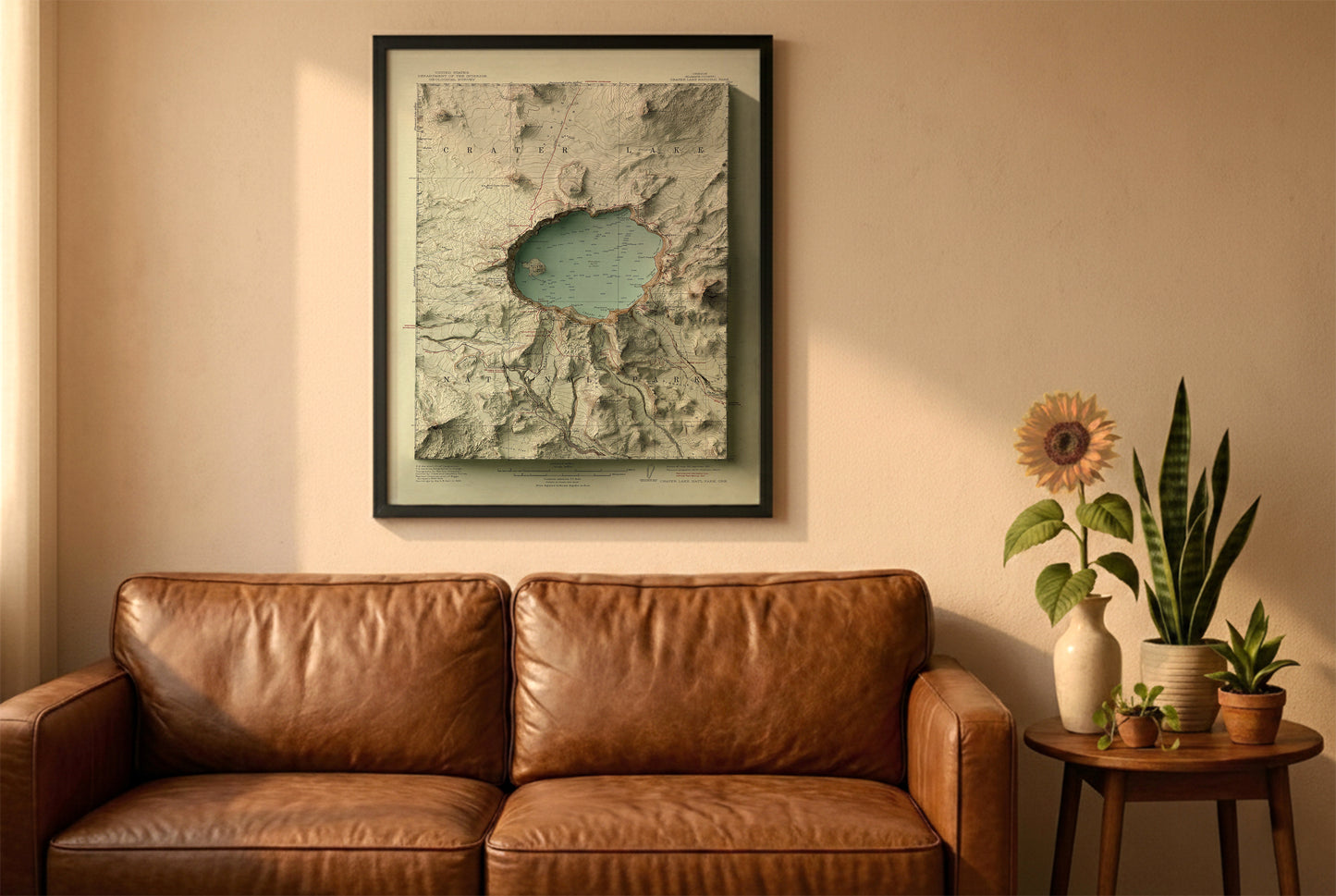 Crater Lake, Oregon, vintage relief map in a black frame above a brown leather sofa. Boho living room with warm sunlight, sunflower, and indoor plants on a wooden side table
