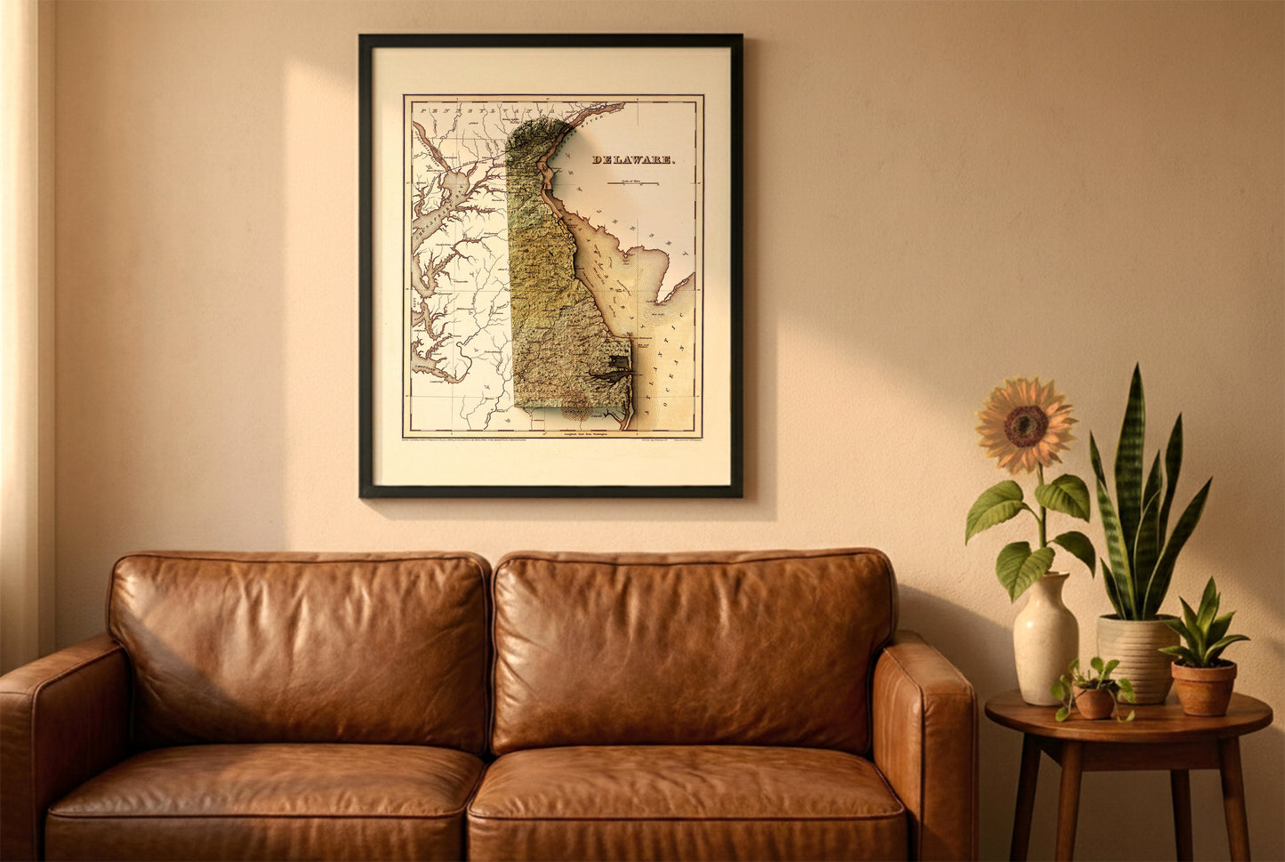 Delaware vintage relief map in a black frame above a brown leather sofa. Boho living room with warm sunlight, sunflower, and indoor plants on a wooden side table
