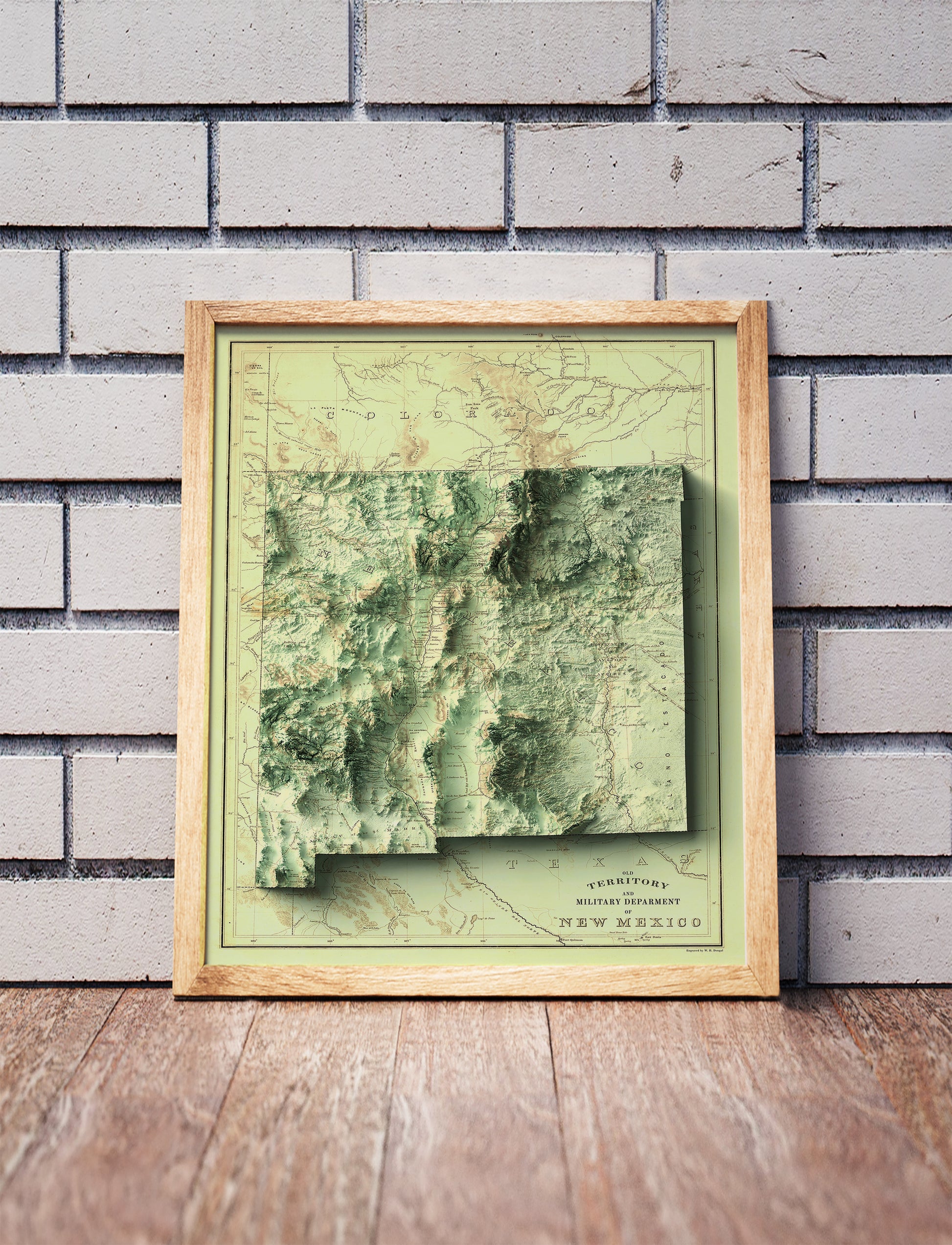 Vintage New Mexico shaded relief map in a wooden frame. Realistic terrain art print for home decor, displayed against a brick wall