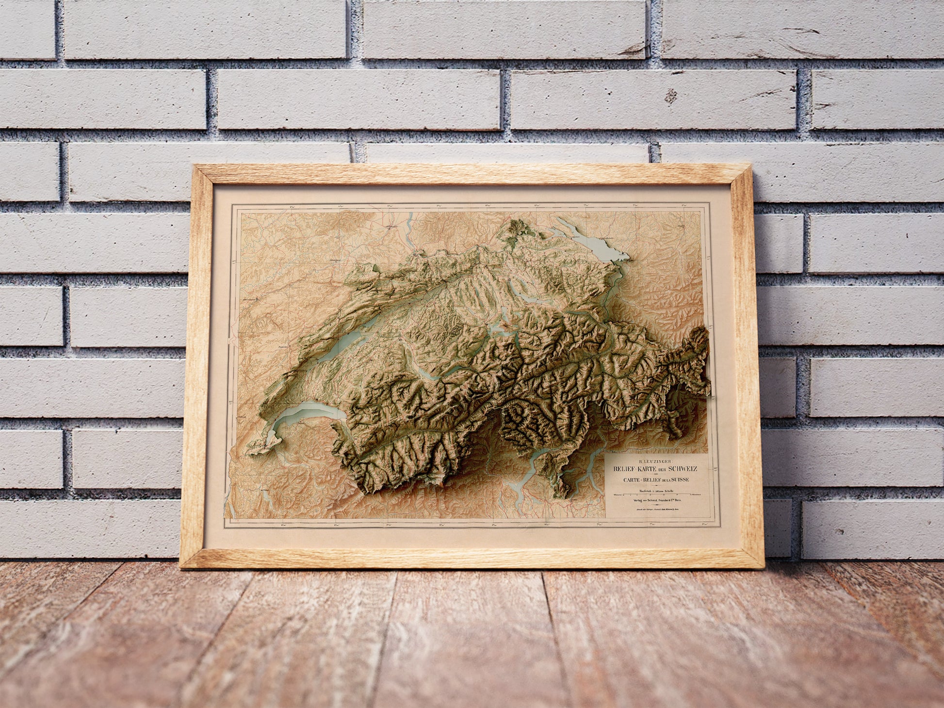 Vintage Switzerland shaded relief map in a wooden frame. Realistic terrain art print for home decor, displayed against a brick wall