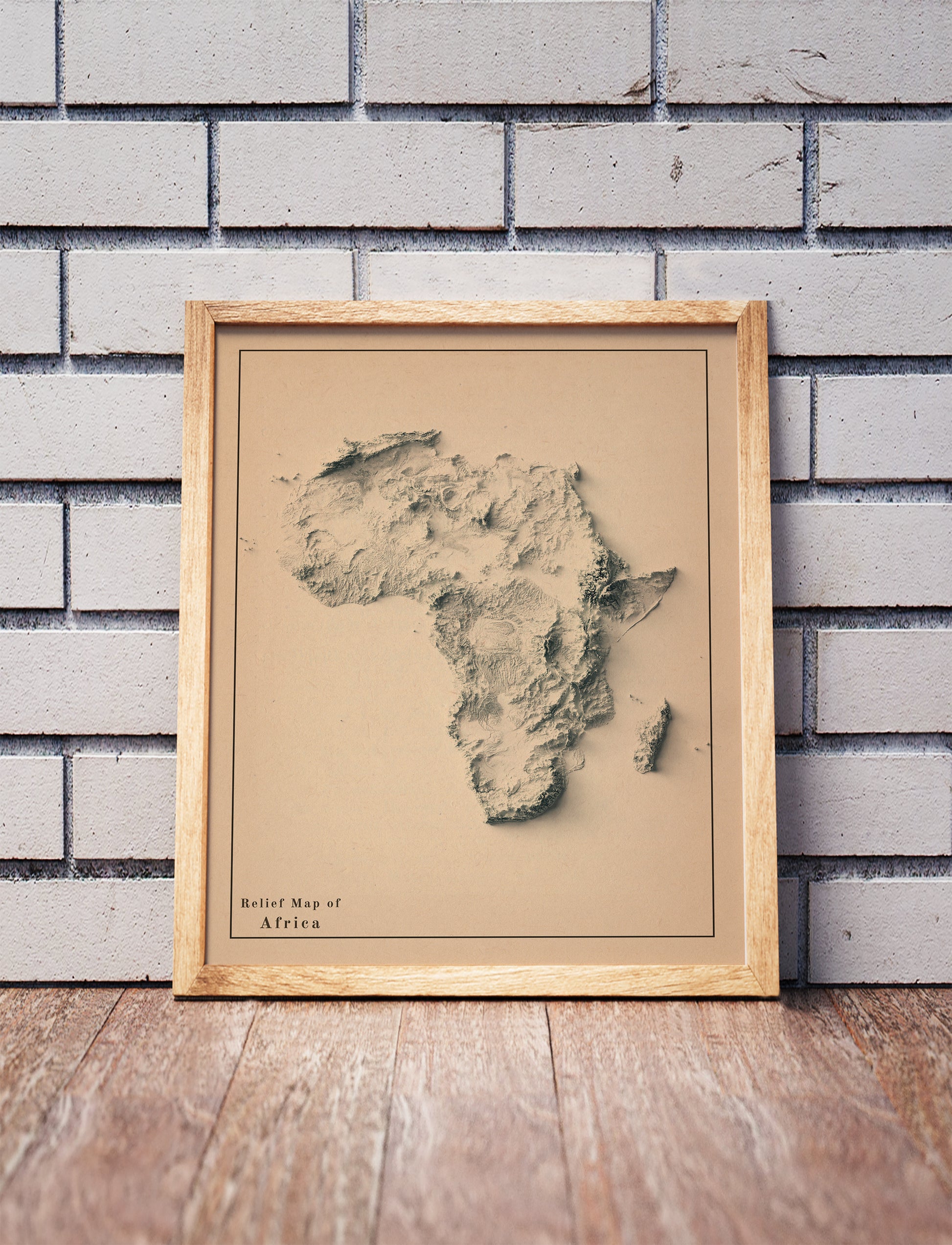 Africa shaded relief map in a wooden frame. Realistic terrain art print for home decor, displayed against a brick wall