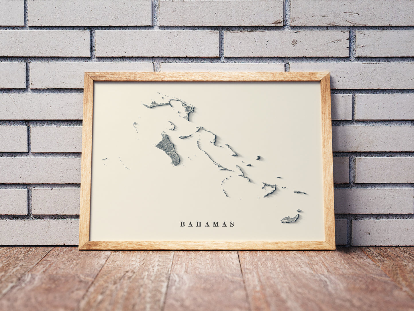 Bahamas shaded relief map in a wooden frame. Realistic terrain art print for home decor, displayed against a brick wall