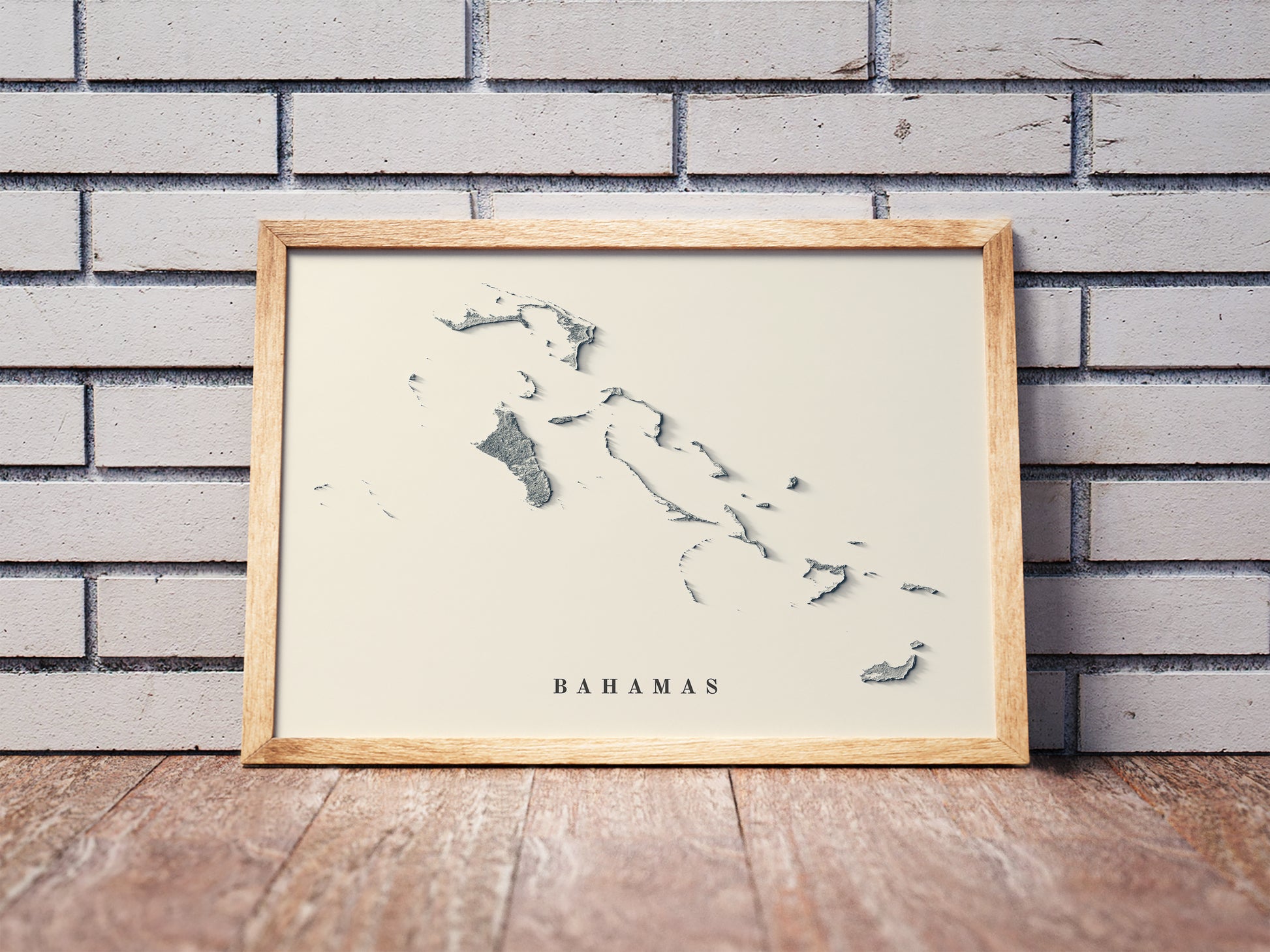 Bahamas shaded relief map in a wooden frame. Realistic terrain art print for home decor, displayed against a brick wall