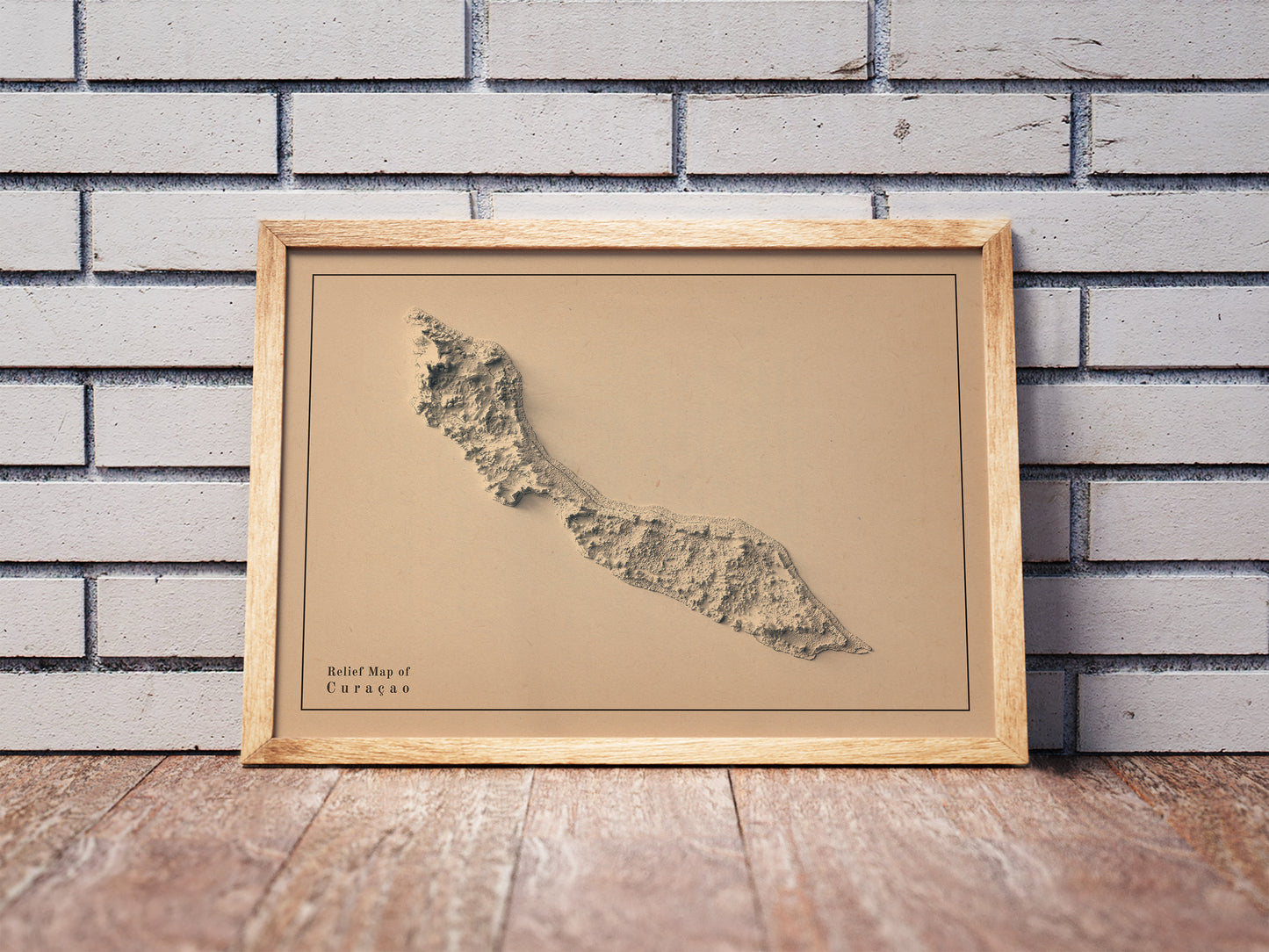 Vintage Curaçao shaded relief map in a wooden frame. Realistic terrain art print for home decor, displayed against a brick wall