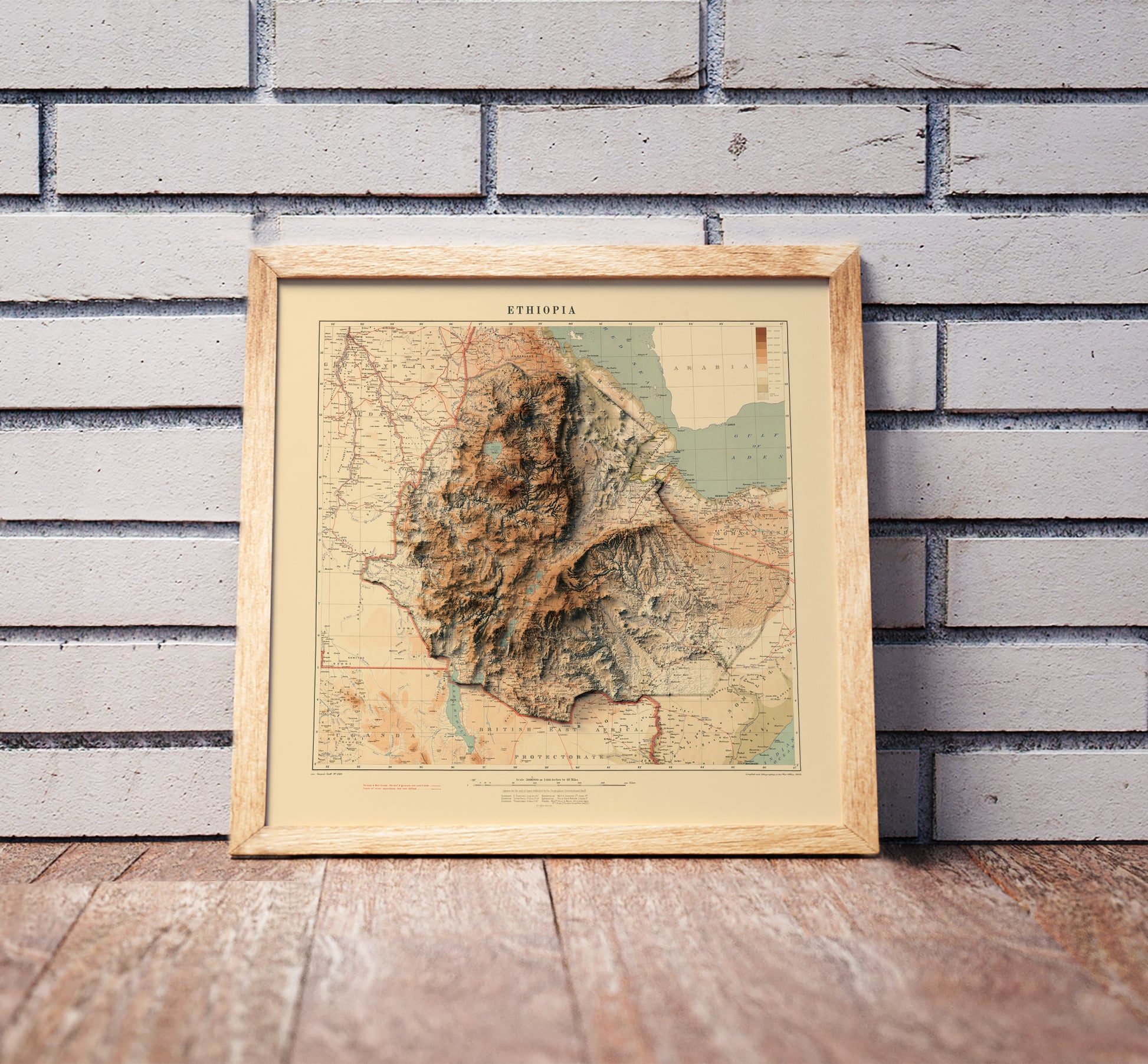Vintage Ethiopia shaded relief map in a wooden frame. Realistic terrain art print for home decor, displayed against a brick wall