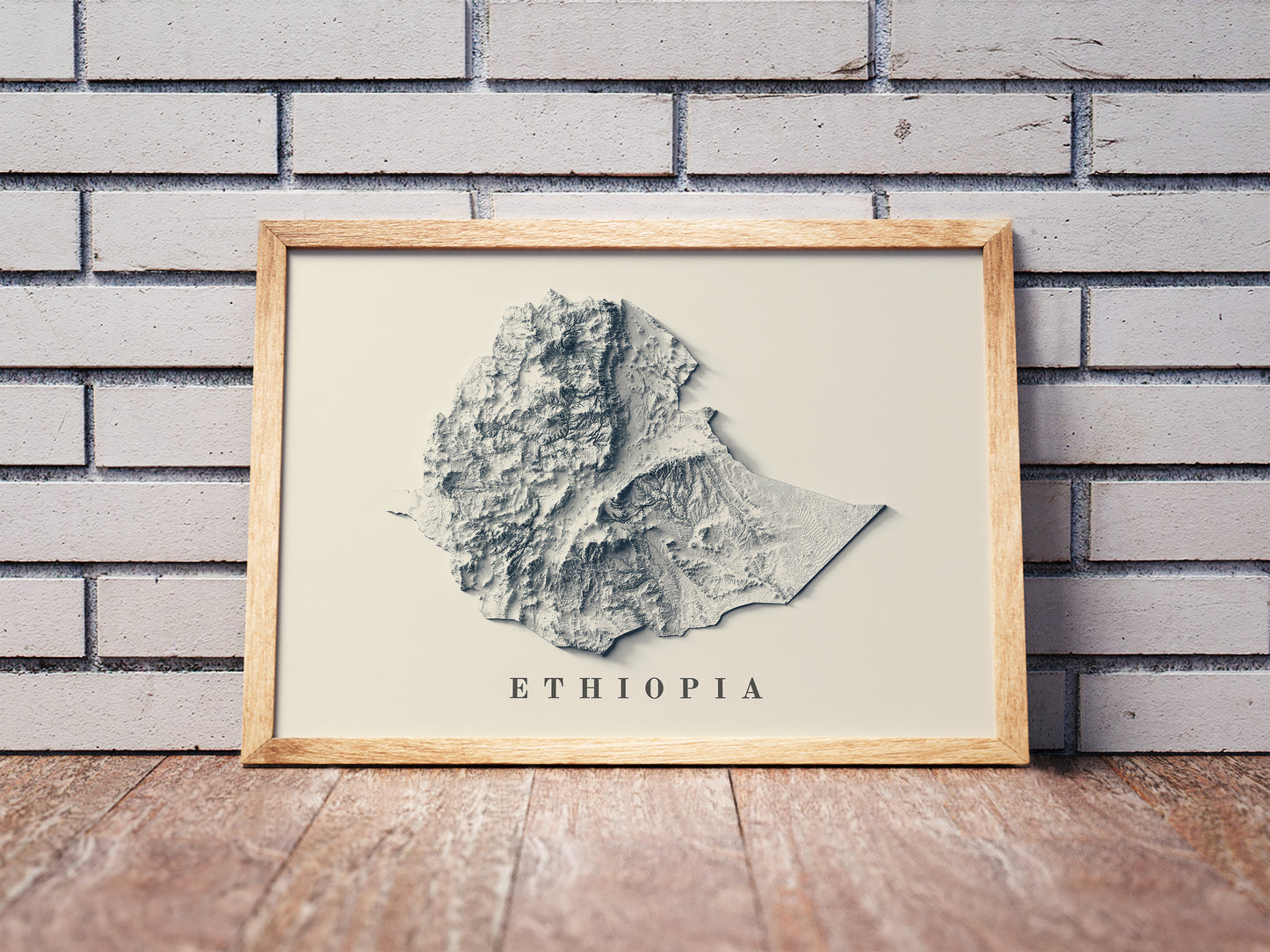 Ethiopia shaded relief map in a wooden frame. Realistic terrain art print for home decor, displayed against a brick wall