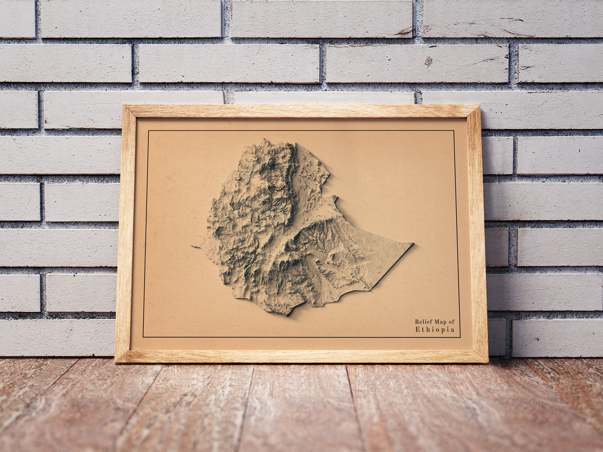 Vintage Ethiopia shaded relief map in a wooden frame. Realistic terrain art print for home decor, displayed against a brick wall