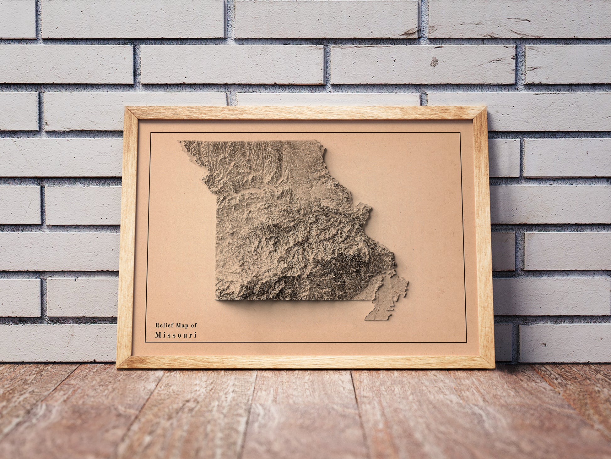 Vintage Missouri USA shaded relief map in a wooden frame. Realistic terrain art print for home decor, displayed against a brick wall
