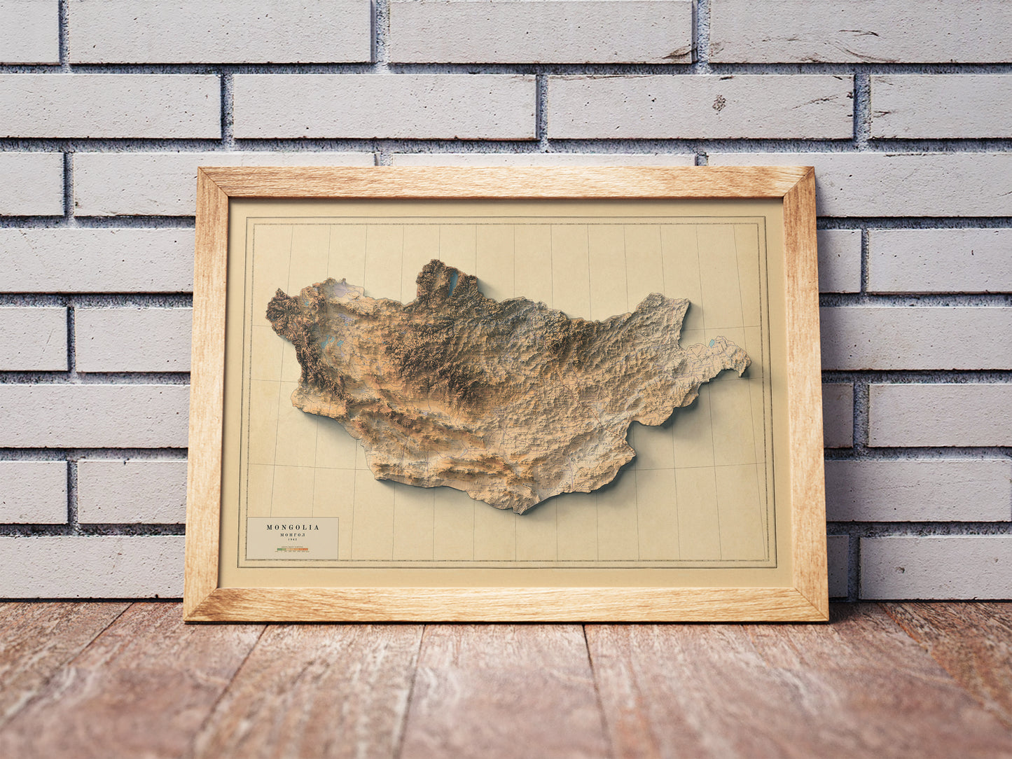 Vintage Mongolia shaded relief map in a wooden frame. Realistic terrain art print for home decor, displayed against a brick wall