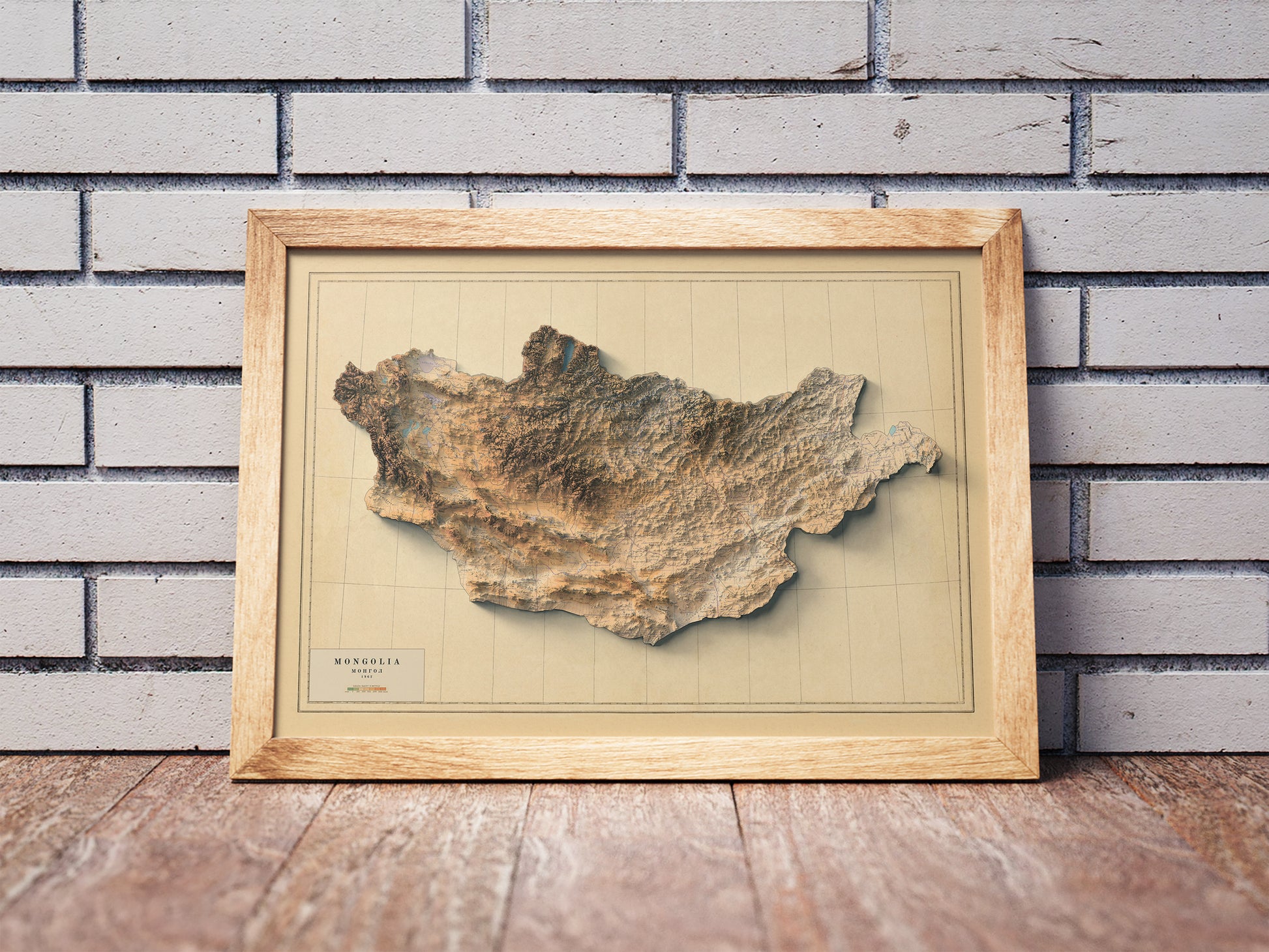 Vintage Mongolia shaded relief map in a wooden frame. Realistic terrain art print for home decor, displayed against a brick wall
