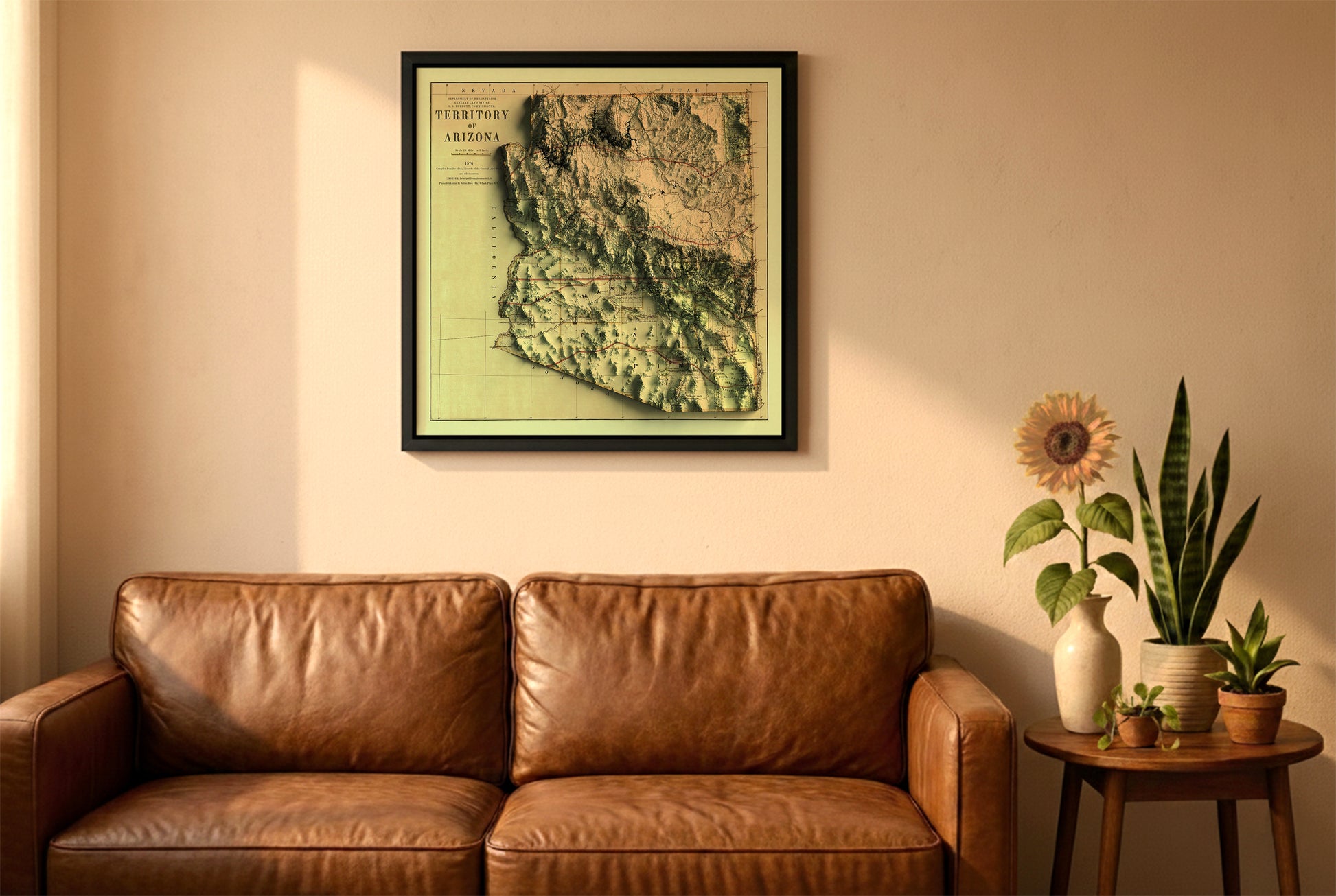 Arizona vintage relief map in a black frame above a brown leather sofa. Boho living room with warm sunlight, sunflower, and indoor plants on a wooden side table