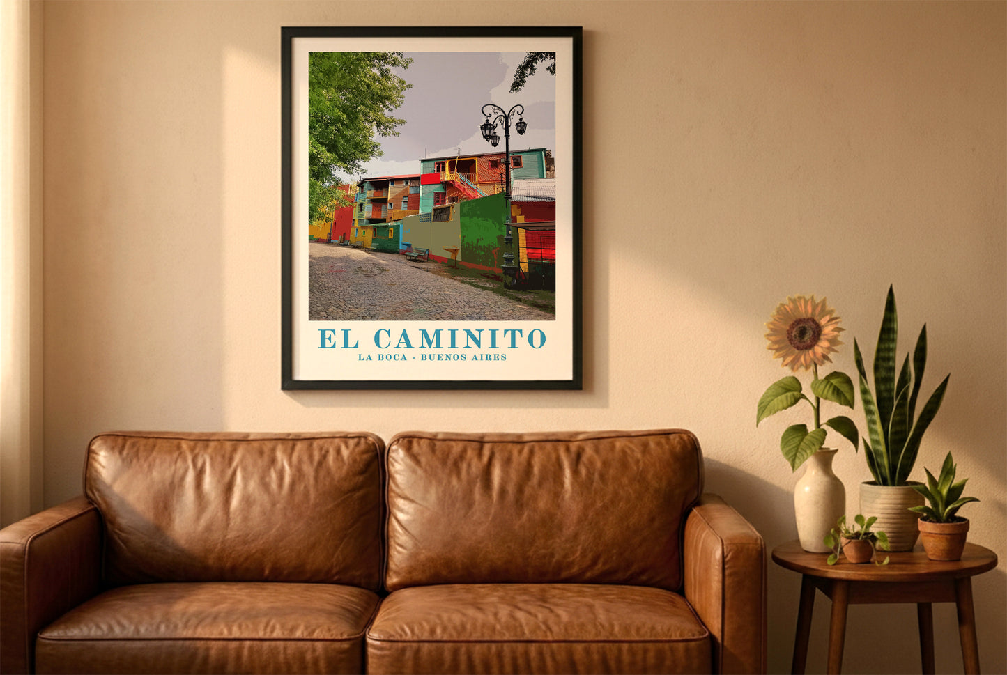 El Caminito, Buenos Aires, poster in a black frame above a brown leather sofa. Boho living room with warm sunlight, sunflower, and indoor plants on a wooden side table
