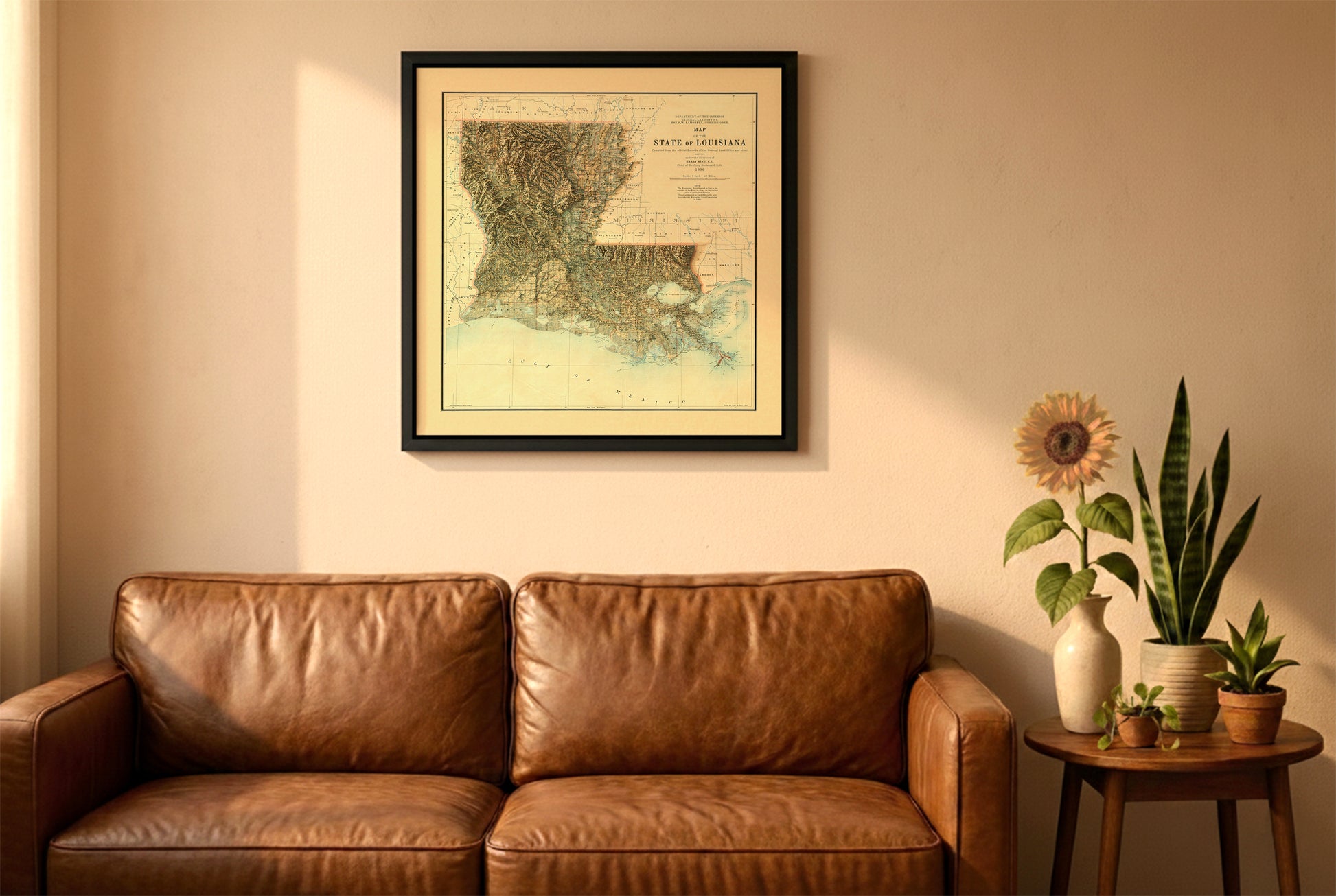 Louisiana vintage relief map in a black frame above a brown leather sofa. Boho living room with warm sunlight, sunflower, and indoor plants on a wooden side table