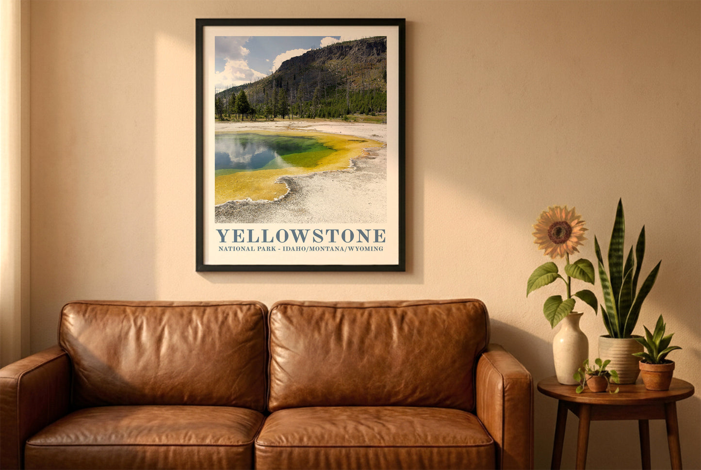 Yellowstone poster in a black frame above a brown leather sofa. Boho living room with warm sunlight, sunflower, and indoor plants on a wooden side table